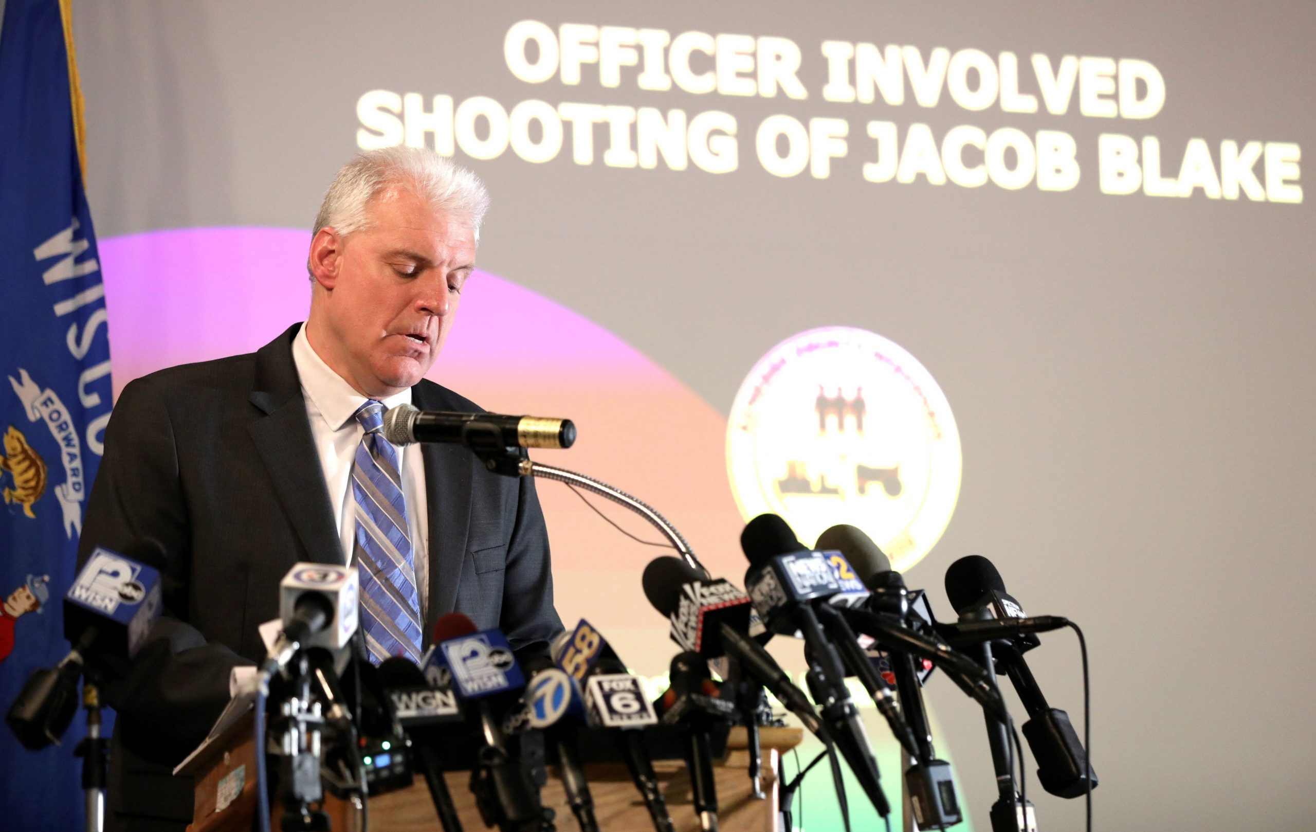 Kenosha County District Attorney Michael Graveley stands in front of microphones at a news conference