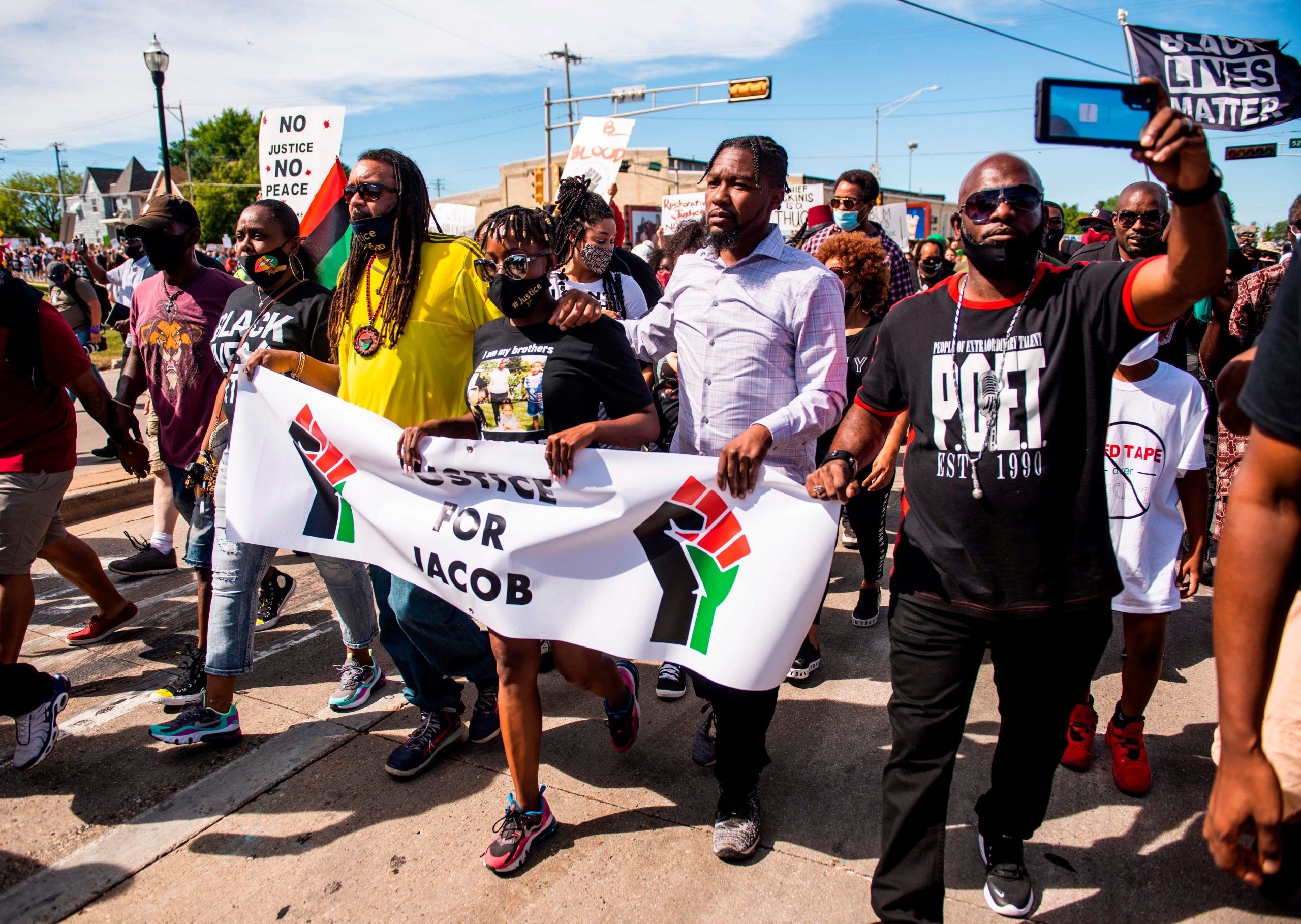 justin blake, letetra wideman, and supporters march holding a sign that says justice for jacob