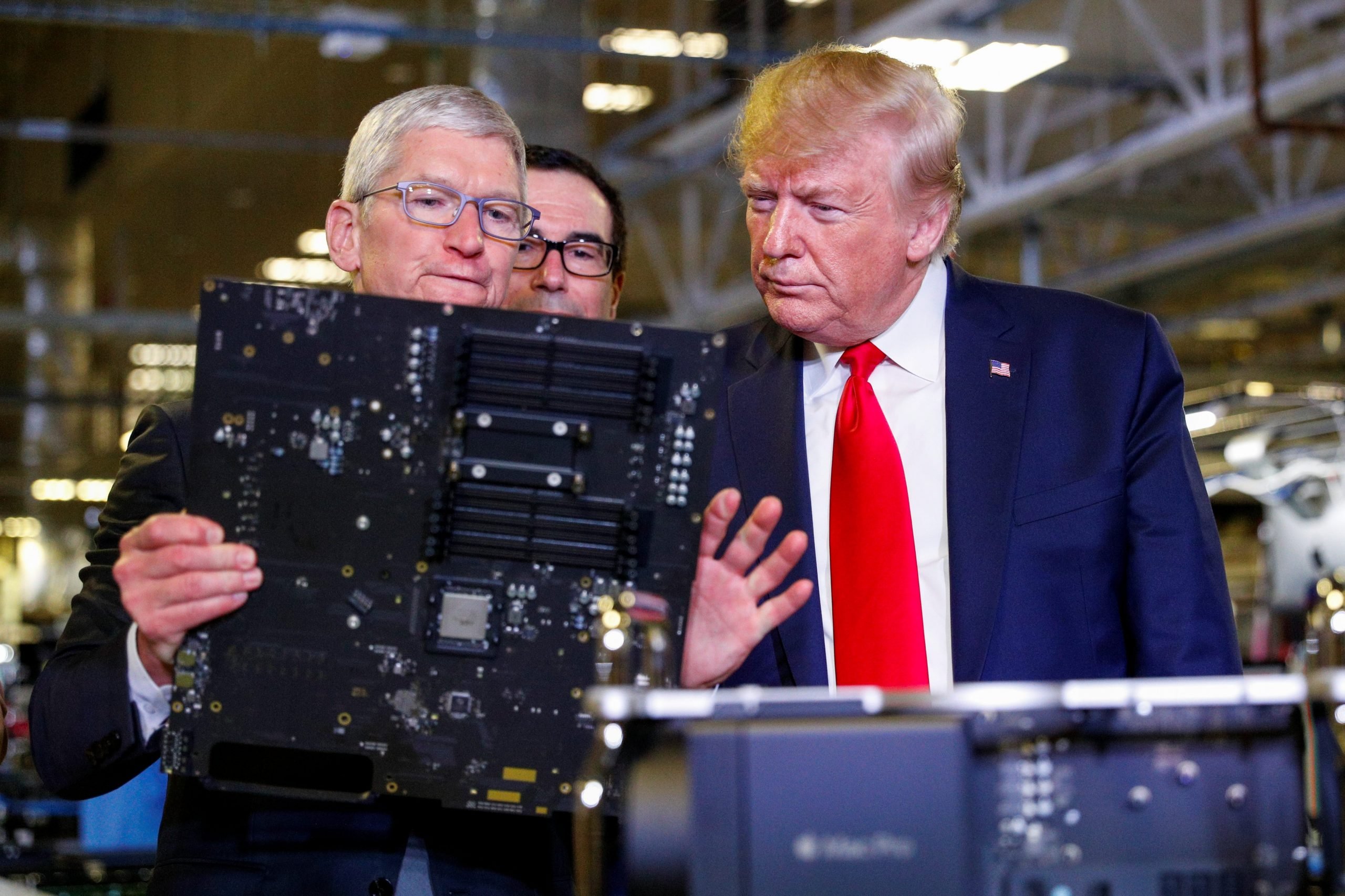 Apple CEO Tim Cook showing President Donald Trump a computer part.