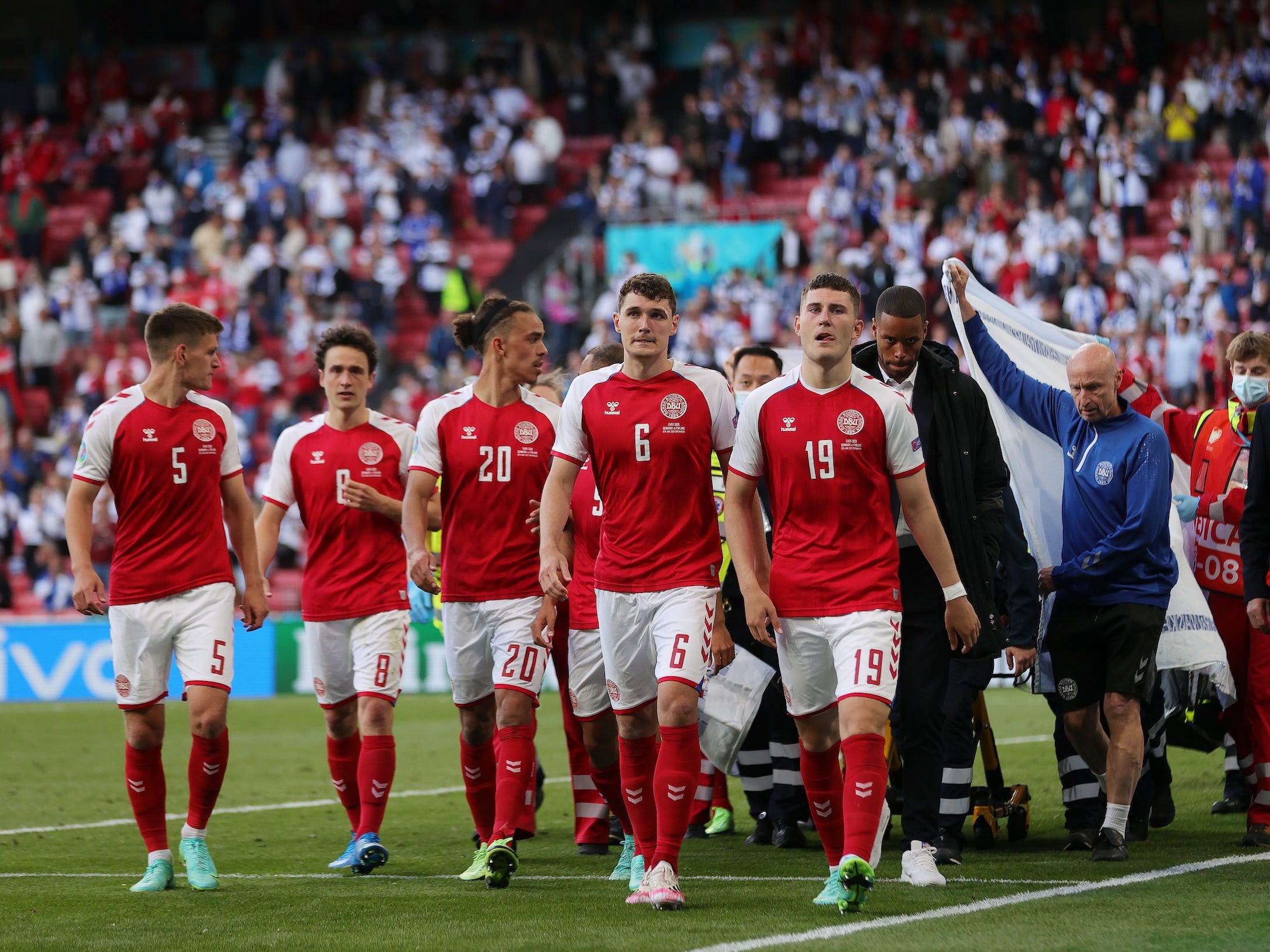 Denmark National Team players escort teammate Christian Eriksen off the pitch following his collapse.