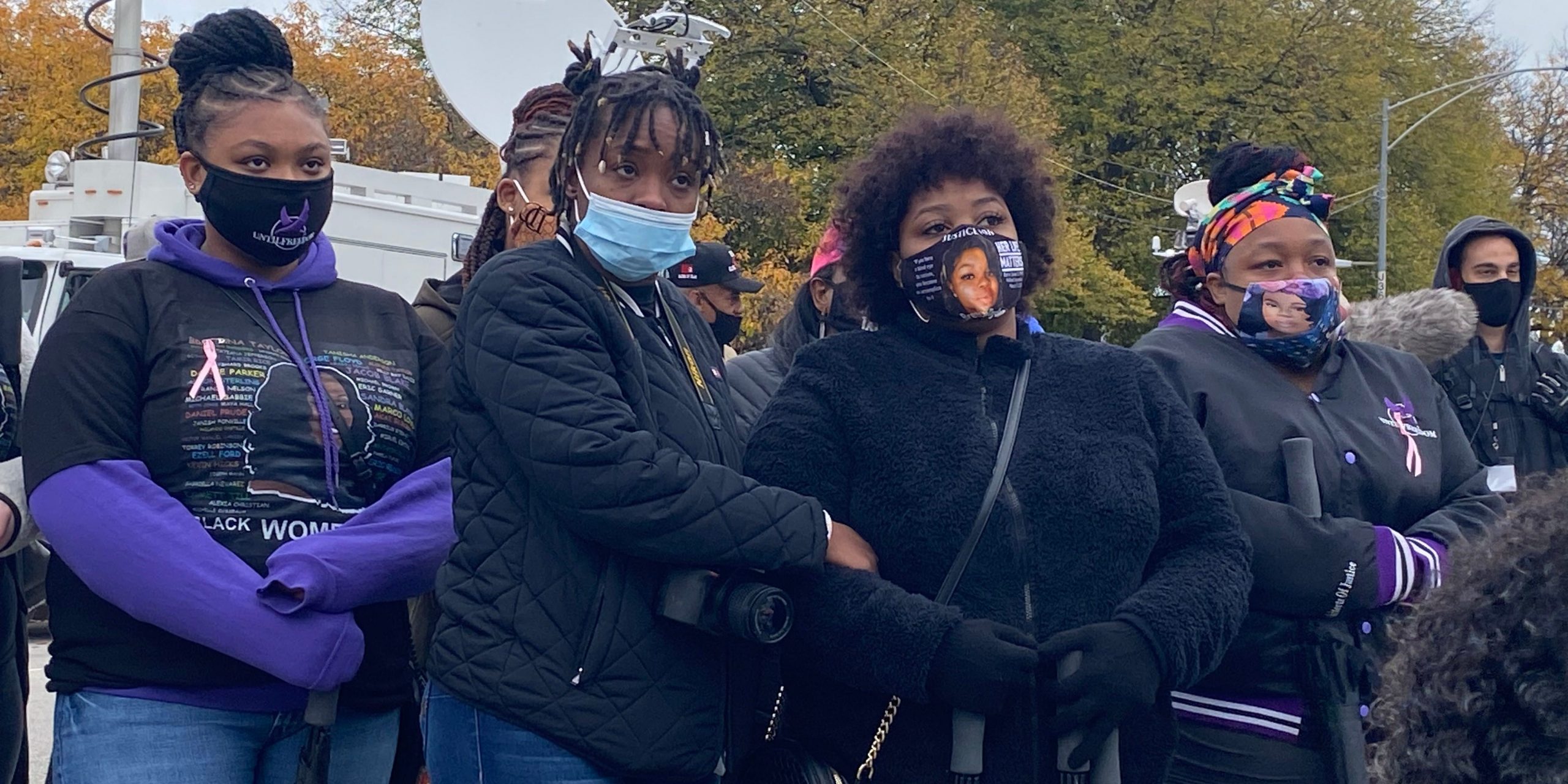 people in masks lock arms outside