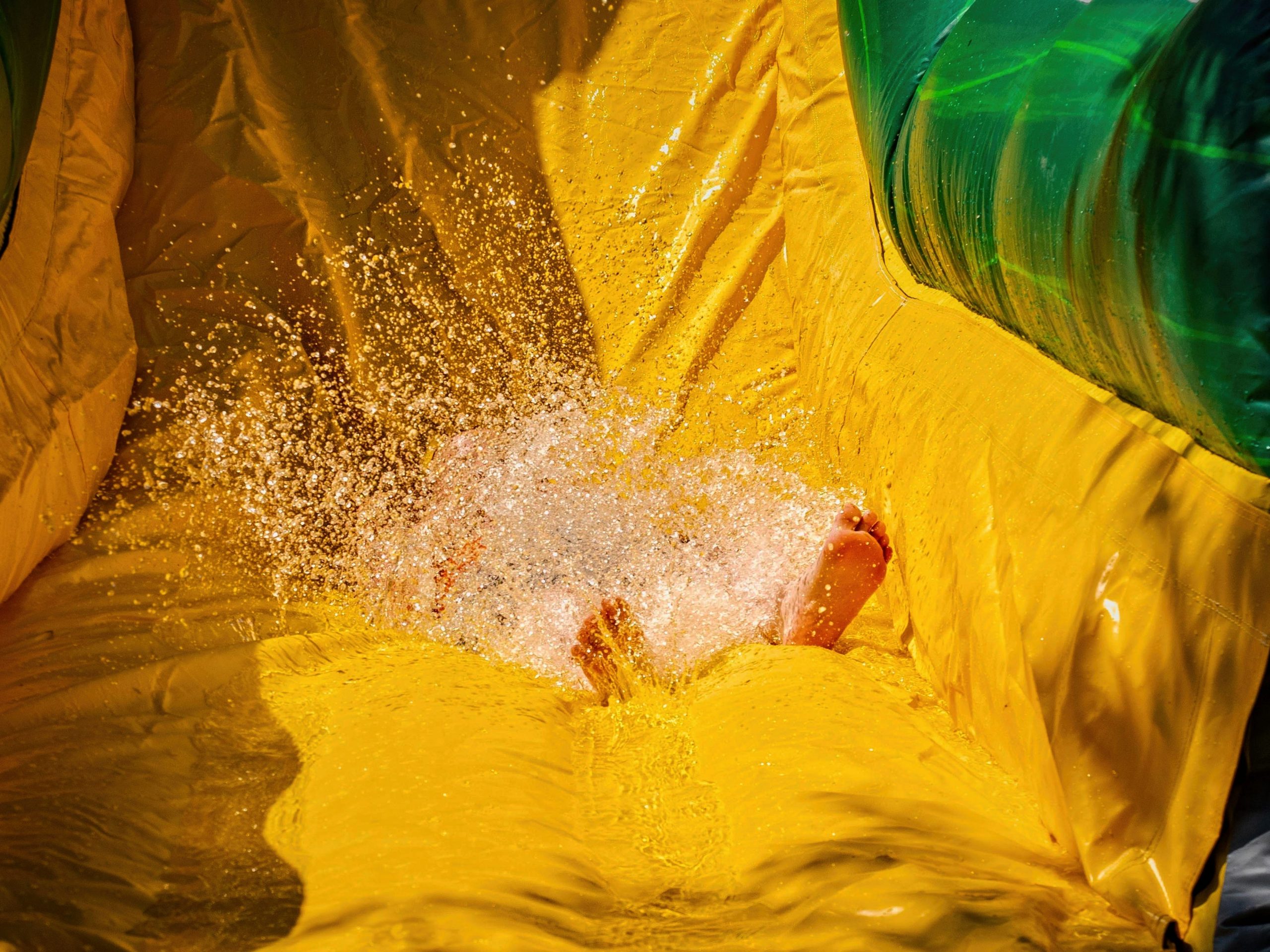 A young child enjoys a water slide.