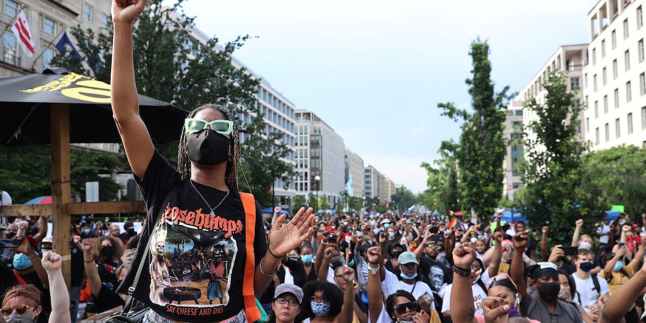 People put their fists in the air as Lift Every Voice and Sing is performed at the intersection of H St NW and 16th Street NW near the White House, an area renamed Black Lives Matter Plaza, while celebrating the Juneteenth holiday June 19, 2020