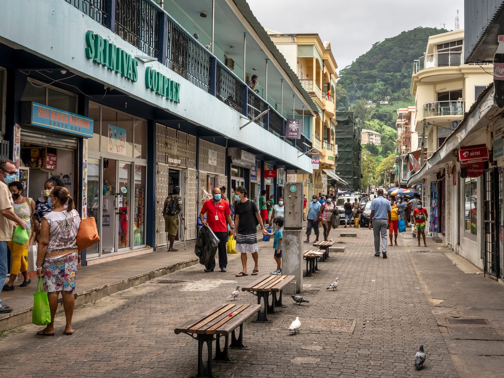 People walking on a commercial street in Seychelles wearing masks