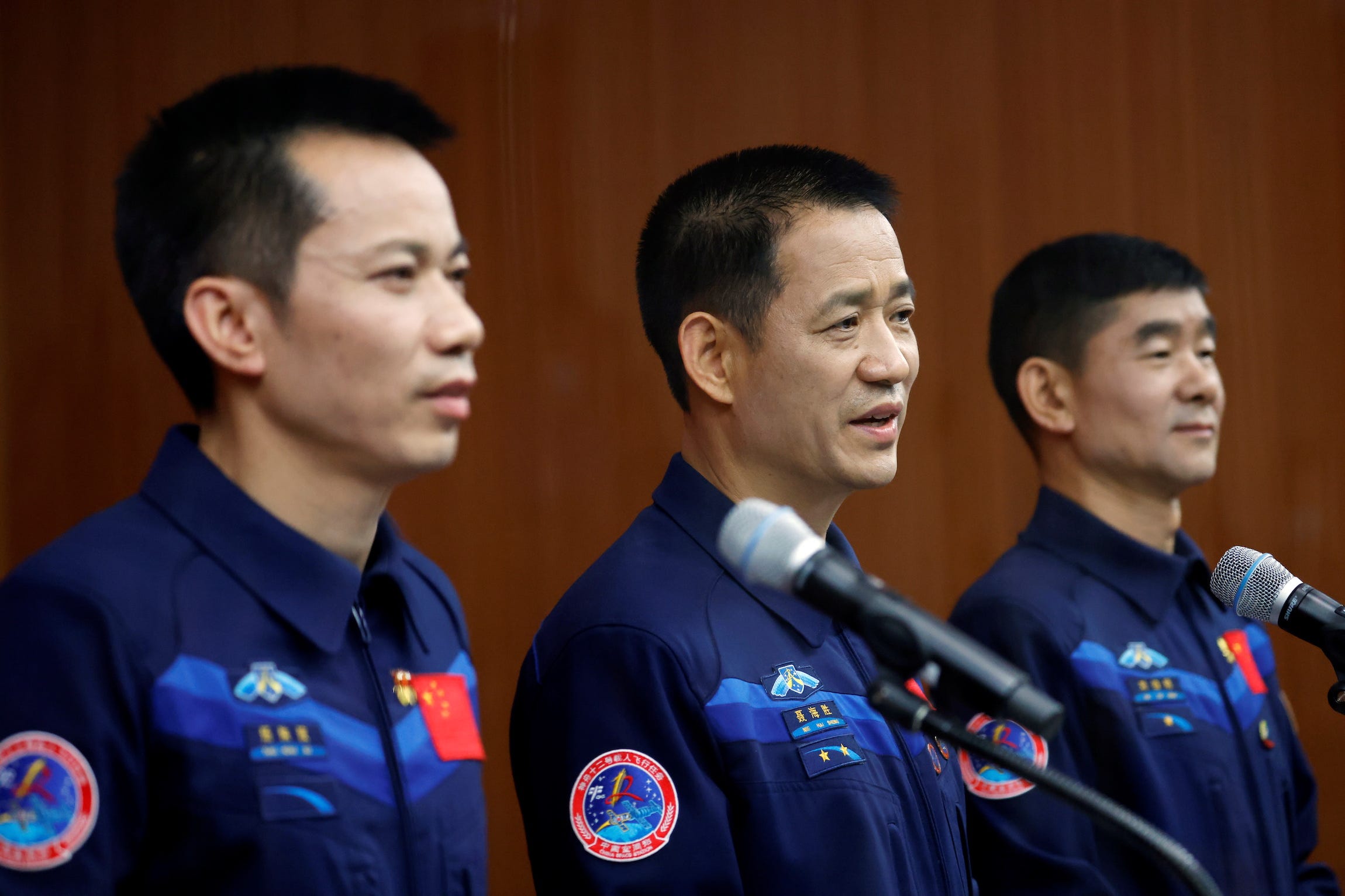 chinese taikonauts Nie Haisheng Liu Boming and Tang Hongbo stand at microphones during a press conference