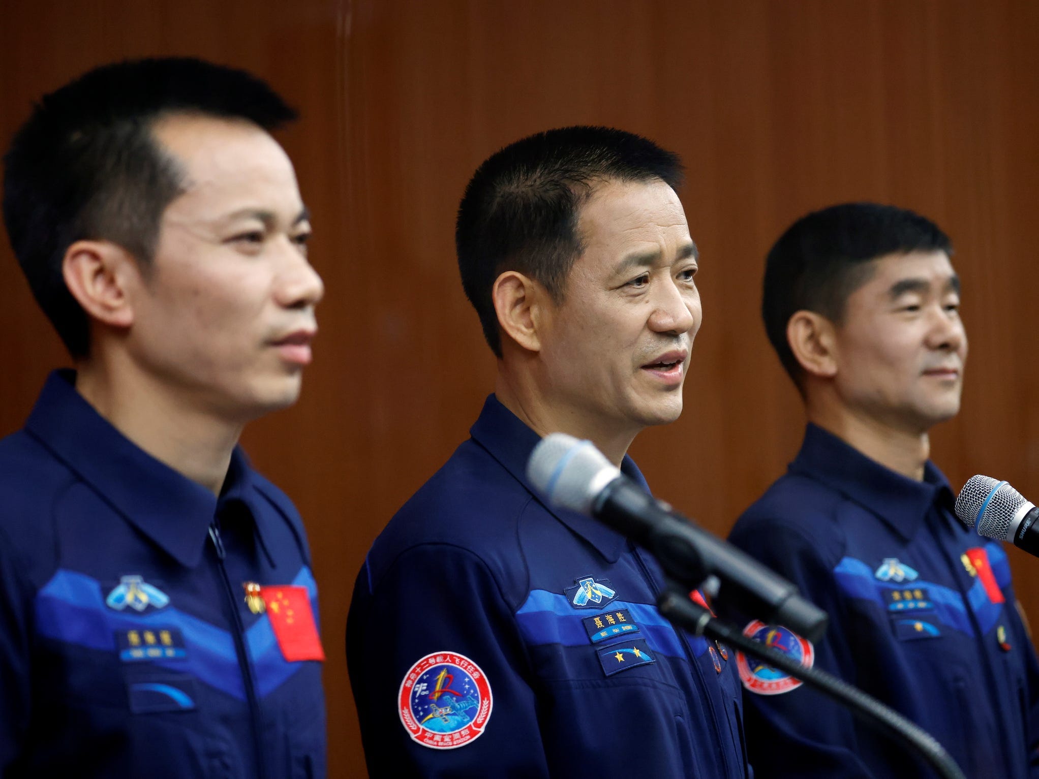 chinese taikonauts Nie Haisheng Liu Boming and Tang Hongbo stand at microphones during a press conference