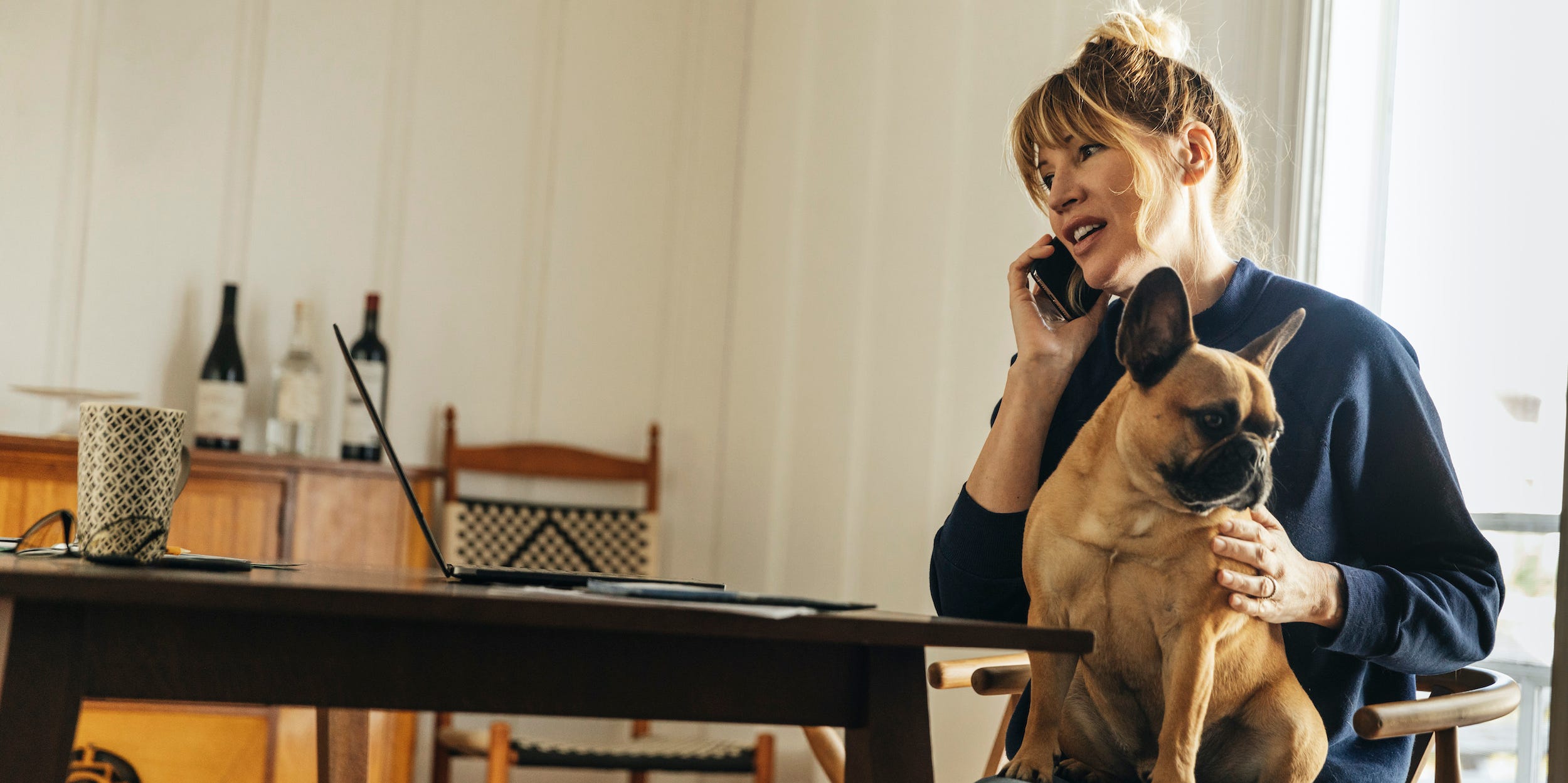 woman at home talking on the phone with dog in lap