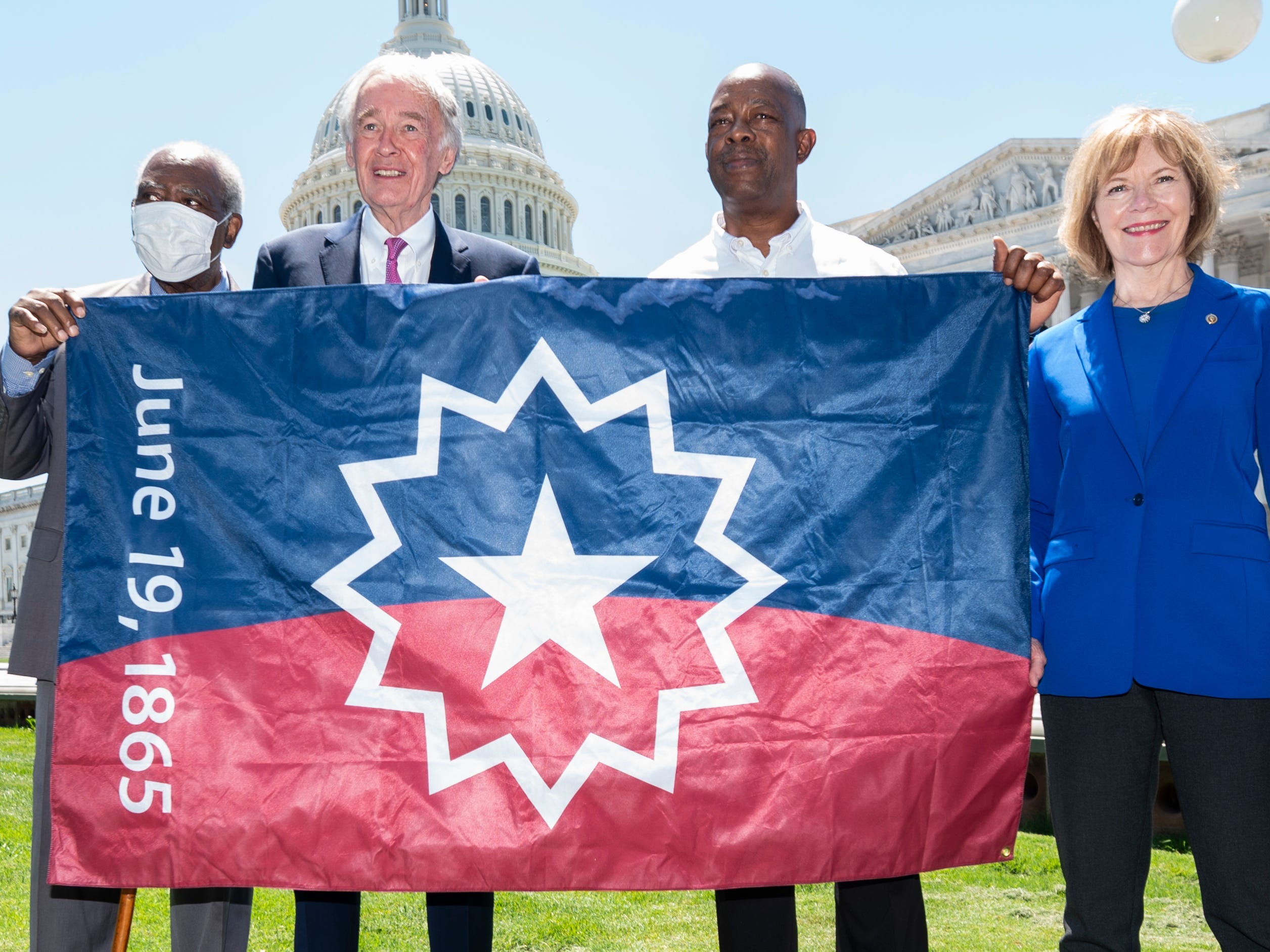 From left, Rep. Danny Davis, D-Ill., Sen. Ed Markey, D-Mass., Steve Williams, president of the National Juneteenth Observance Foundation, and Sen. Tina Smith, D-Minn., pose with the Juneteenth flag in front of the Capitol building in Washington D.C.