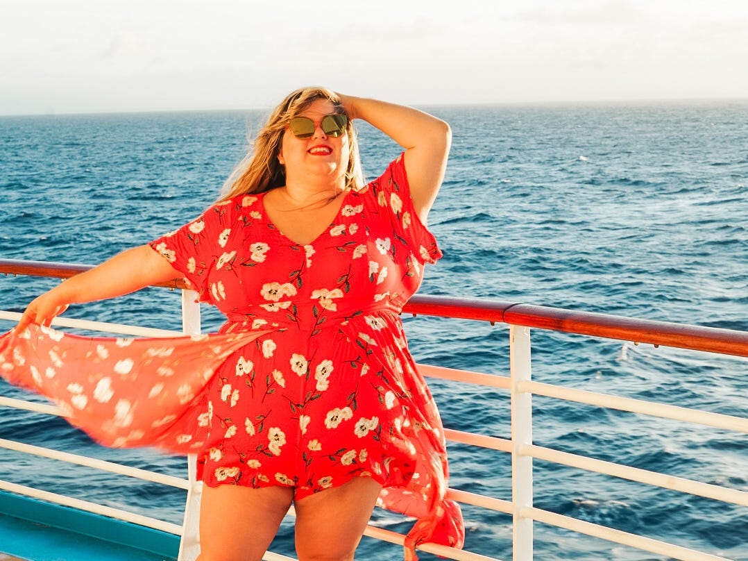 Halee Whiting standing on a cruise in a red dress with sunglasses