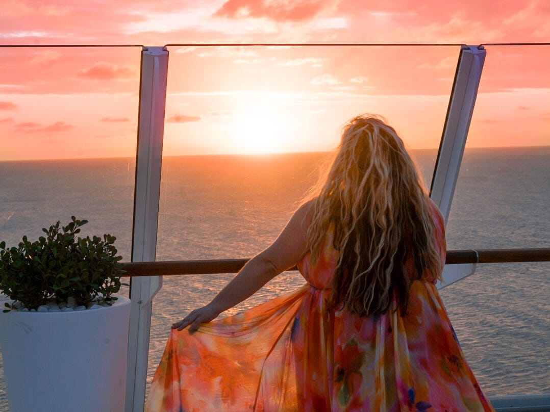 Halee Whiting standing in front of a sunset in an orange dress
