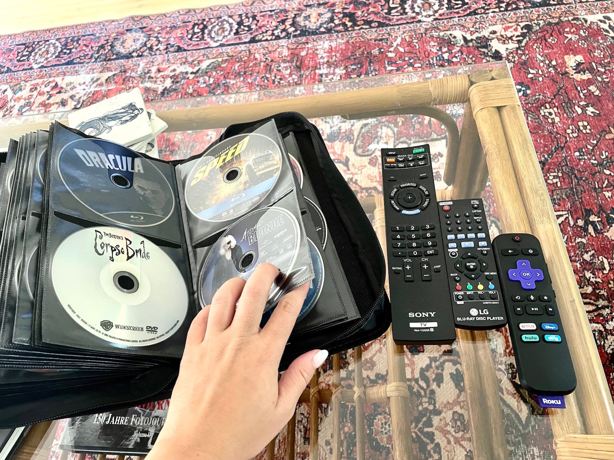 A case holds DVDs next to remotes on a table