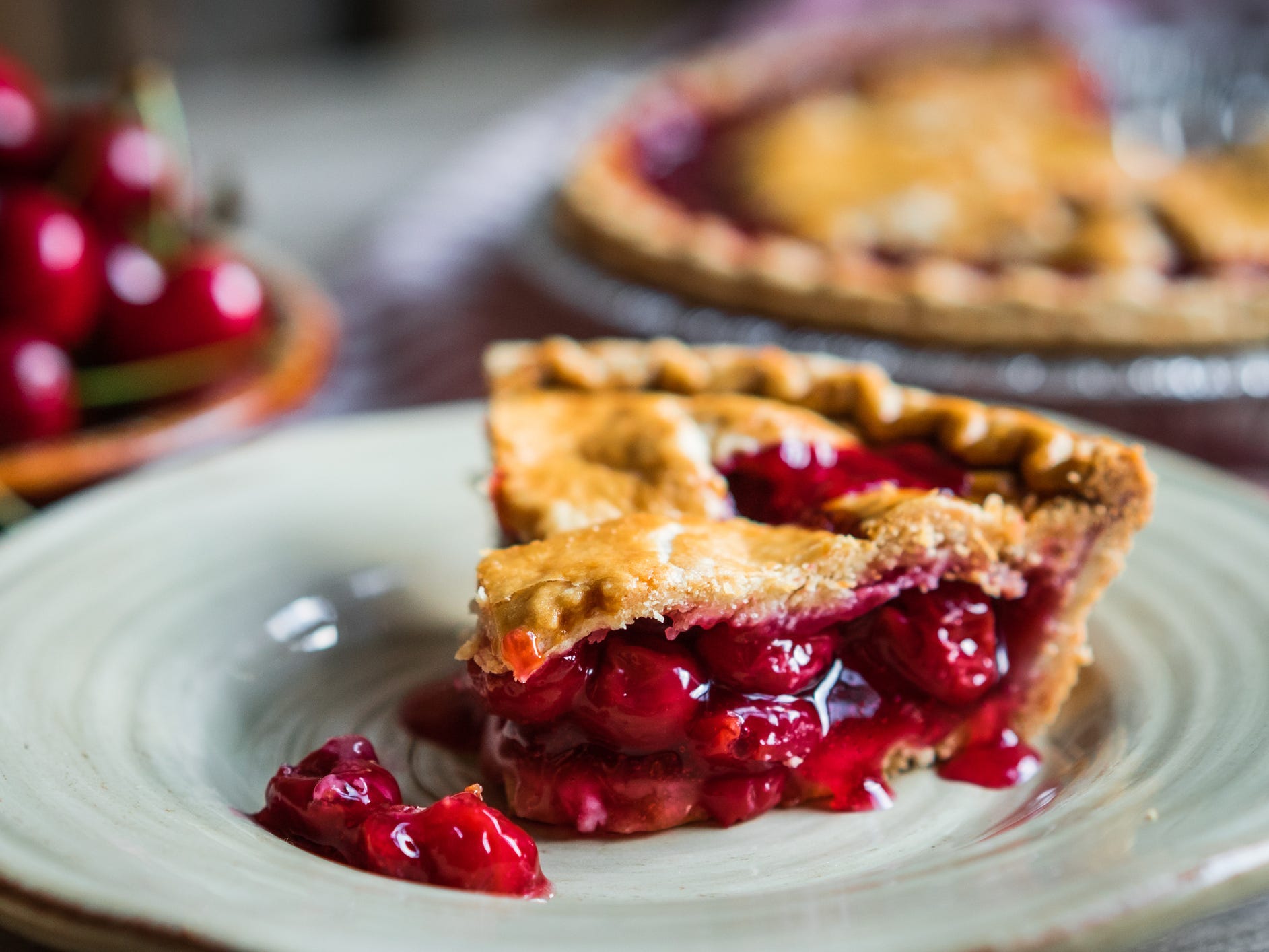 A slice of cherry pie on a green plate