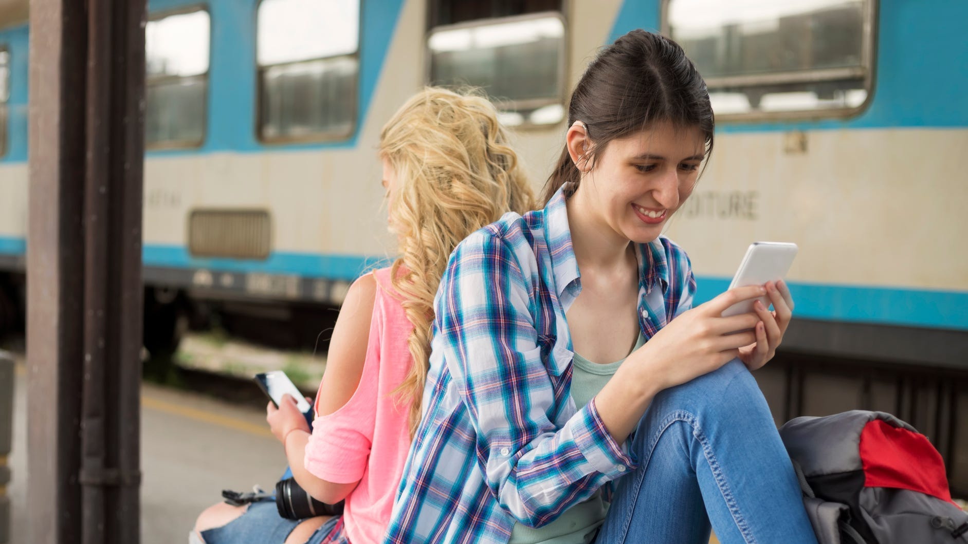 hard of hearing person sits at train stop while texting.