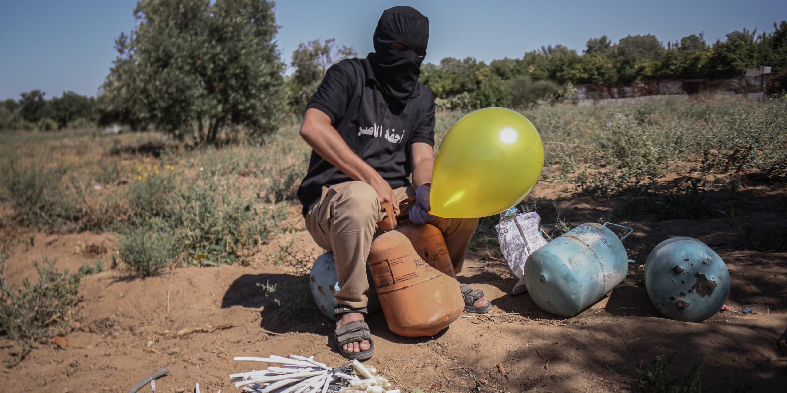 A masked Palestinian supporter of the Al-Nasir Salah Al-Din Brigades prepares incendiary balloons to launch across the border fence east of Gaza city towards Israel, on June 16, 2021 east of Gaza City in Gaza. The flare-up came after a controversial flag-waving march by Israeli nationalists was allowed to proceed through East Jerusalem on Tuesday, stoking tensions in Israel and Gaza less than a month after a ceasefire ended 11 days of fighting between Hamas and Israeli forces.