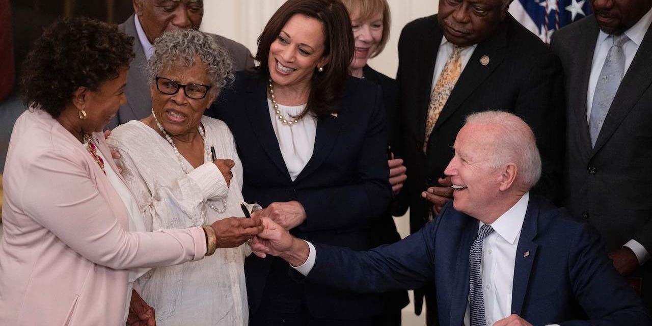 Opal Lee (2nd L), the activist known as the grandmother of Juneteenth, US Vice President Kamala Harris look on as US President Joe Biden gives a pen to US Congresswoman Barbara Lee (L) after signing the Juneteenth National Independence Day Act.
