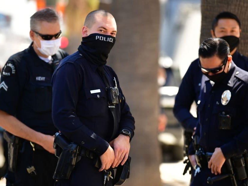 Four Los Angeles Police Department officers stand outside wearing face masks.