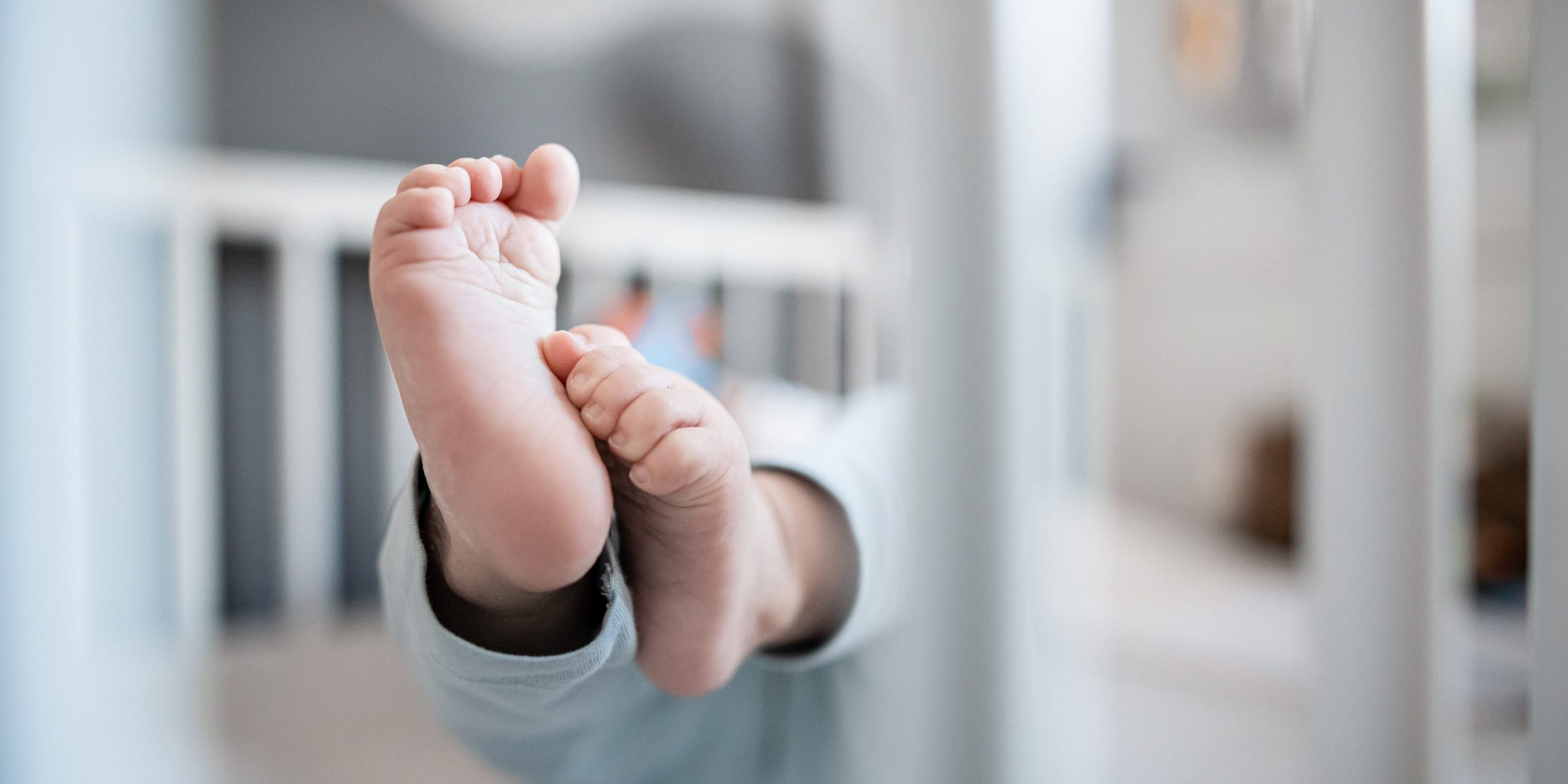 A baby's feet are seen in a crib