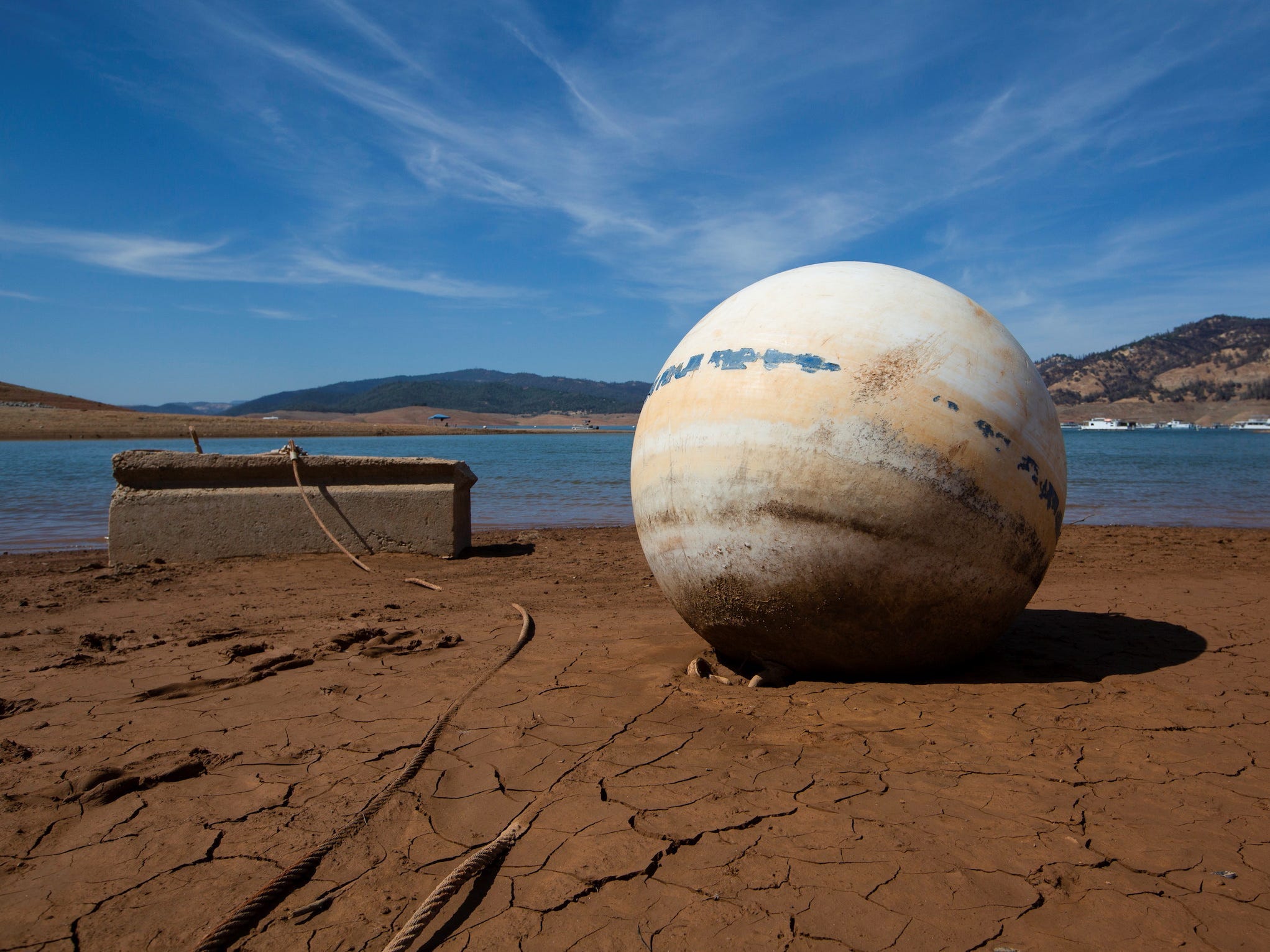 buoy and concrete anchor lay on cracked ground where lake oroville has dried up