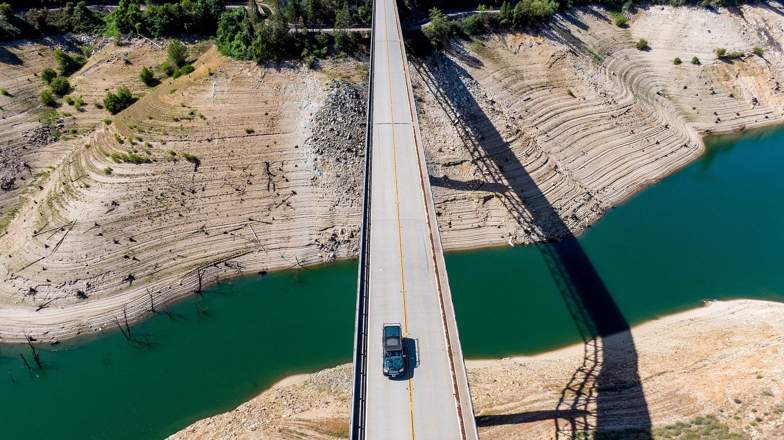 car drives across bridge over lake oroville's dry banks