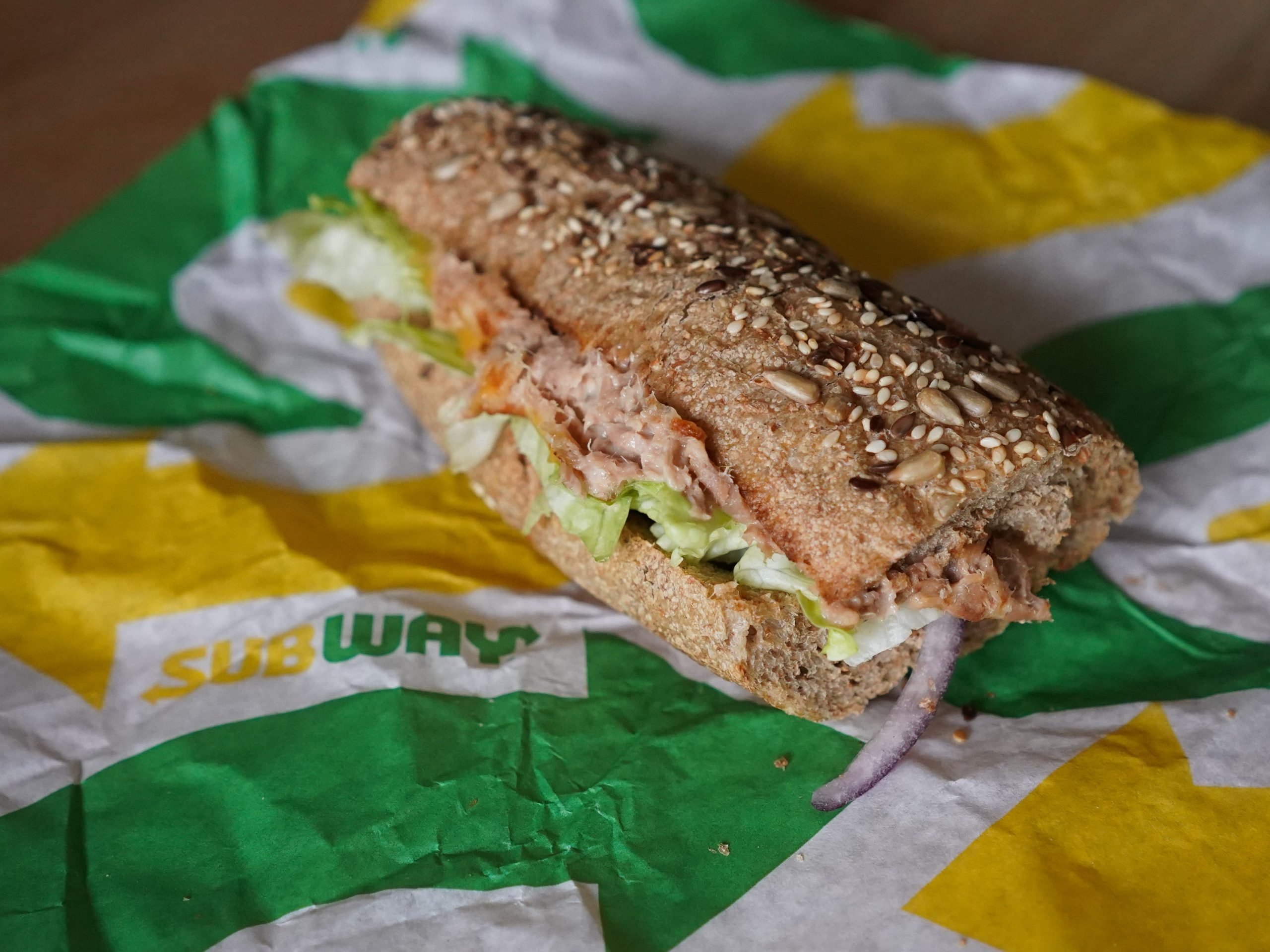 tuna sandwich with lettuce and tomato on wrapper paper