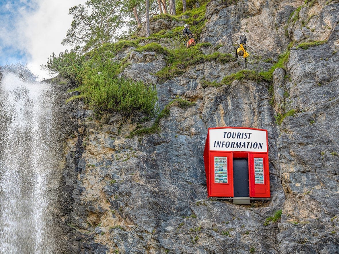 A bright red tourism book is embedded in the rock of a mountain.