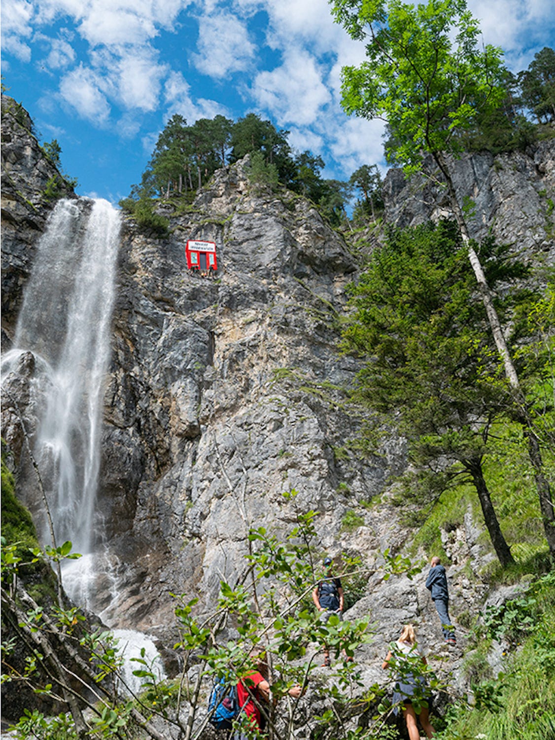 A bright red tourism book is embedded in the rock of a mountain.