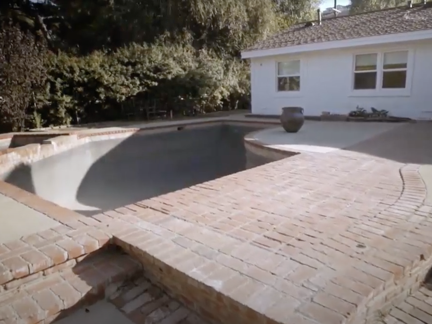 A concrete patio with an empty pool.