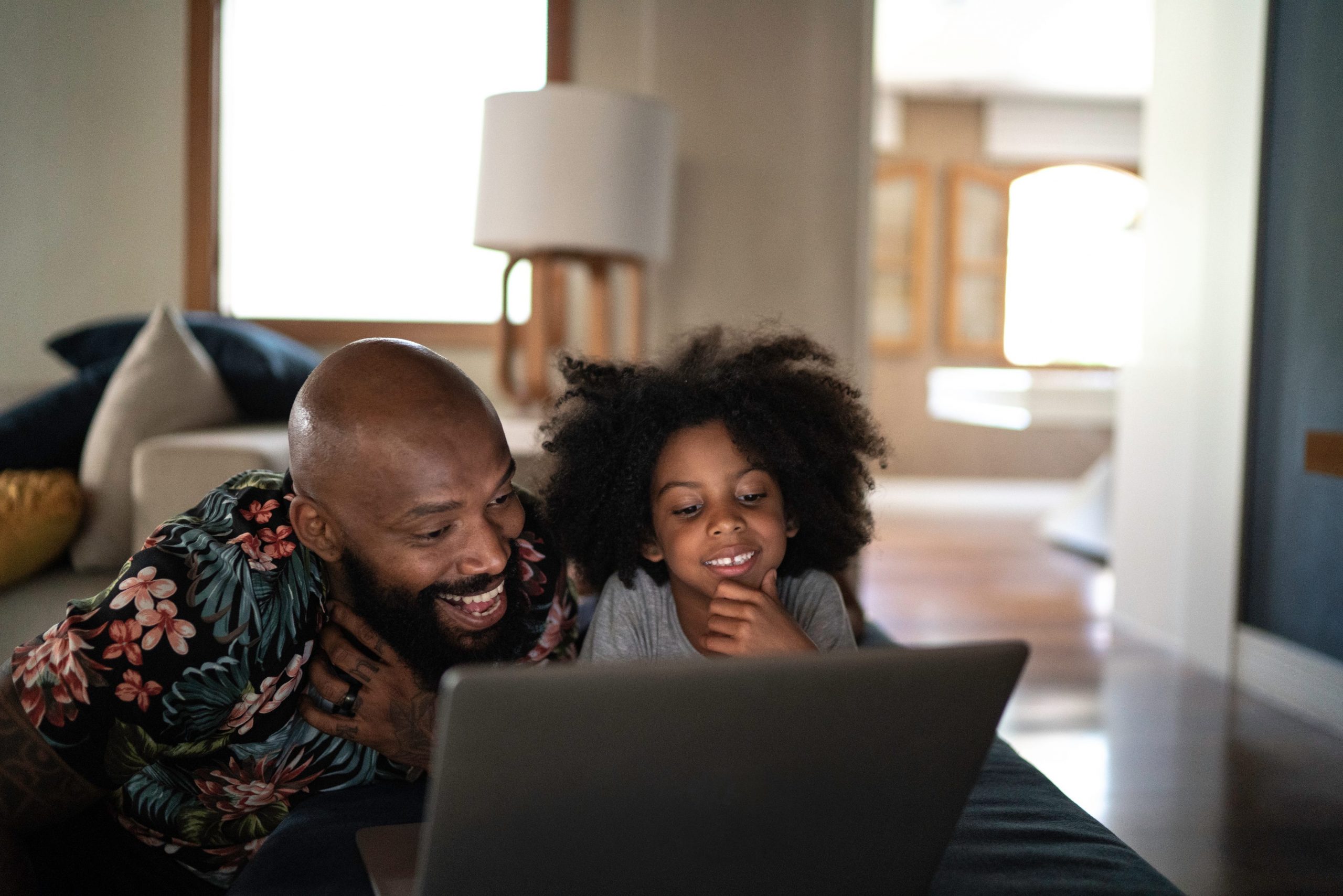 A father and daughter watch TV on a laptop together