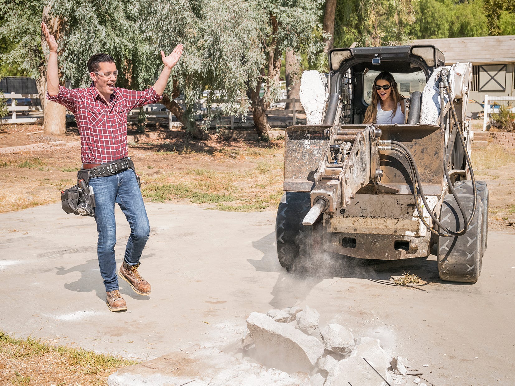 Kendall Jenner drives an excavator while a Property Brother looks on.