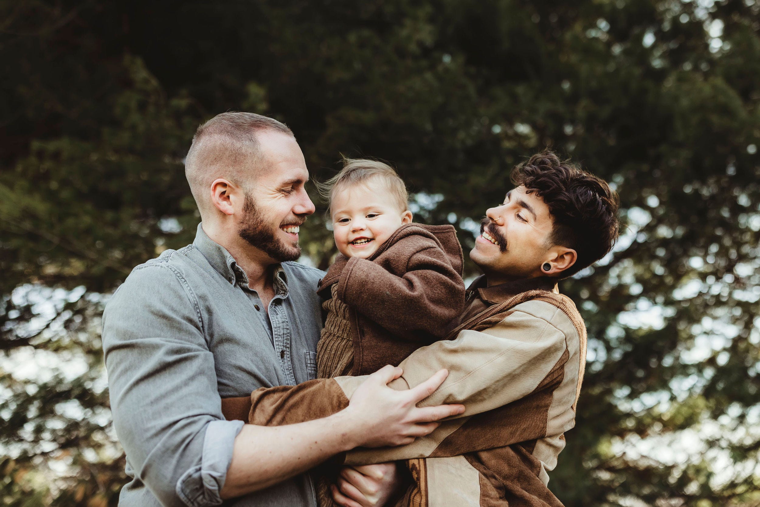 Matt Durt (left) and his daughter Uma and husband Elliot all hold each other, smiling outside.