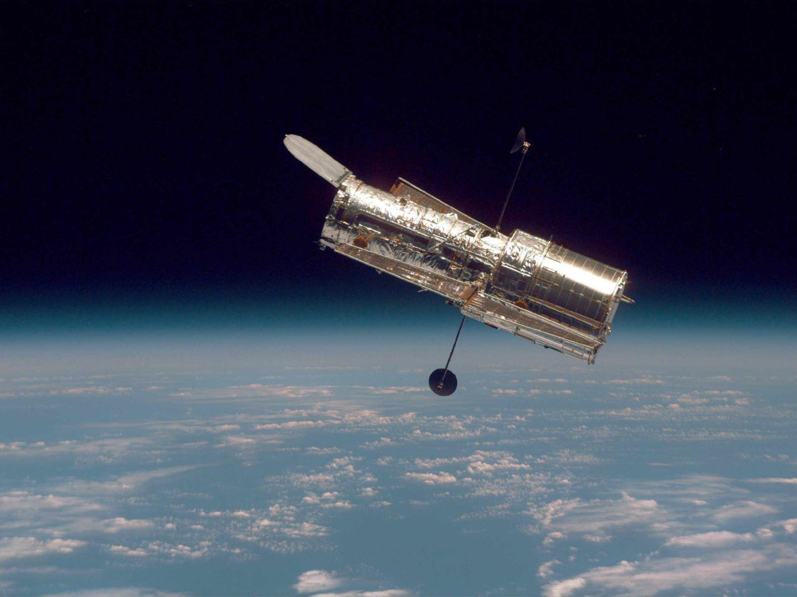 hubble telescope in space above earth clouds