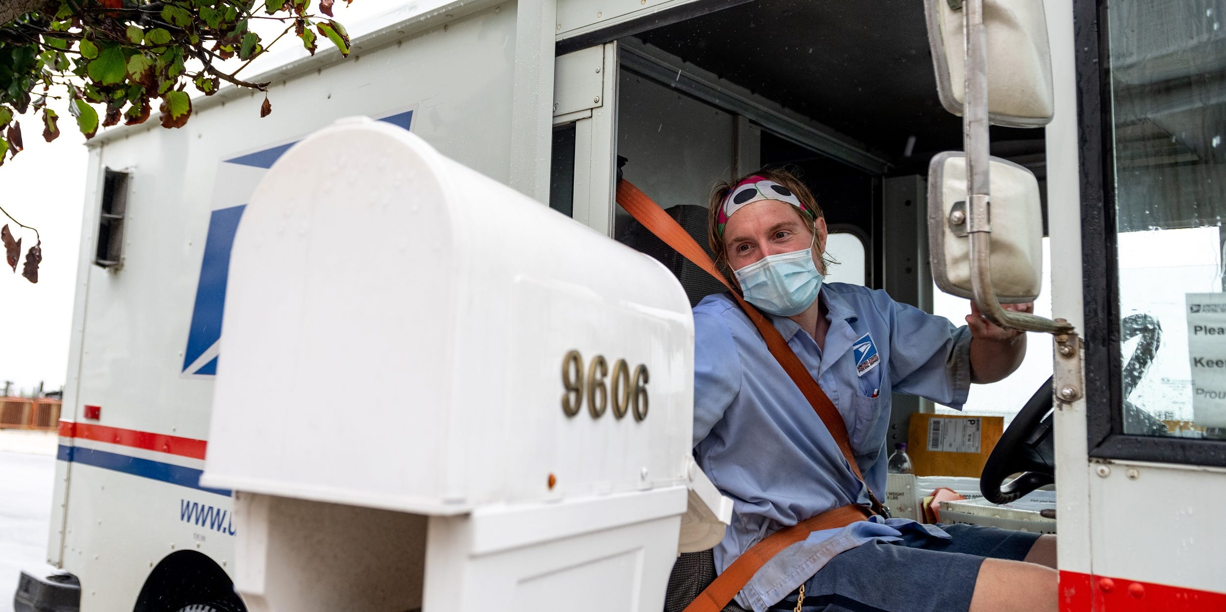 VENTNOR CITY, NEW JERSEY - AUGUST 13: A USPS worker wearing a mask puts envelopes in a mailbox while driving past as the state of New Jersey continues Stage 2 of re-opening following restrictions imposed to slow the spread of coronavirus on August 13, 2020 in Ventnor City, New Jersey. Stage 2, allows moderate-risk activities to resume which includes pools, youth day camps and certain sports practices. (Photo by Alexi Rosenfeld/Getty Images)