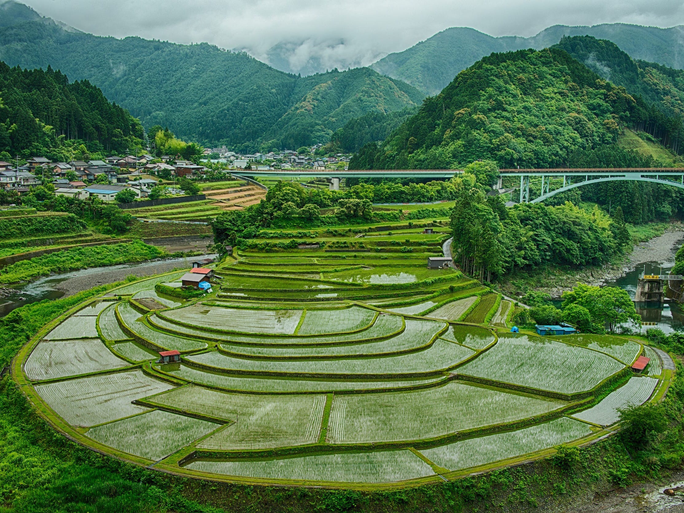 This quiet valley with rice terraces is virtually unknown to anyone except locals. Several shades of green can be seen in this beautiful and misty place. With a small village where the townsfolk live in. The mountains in the background tower over it.