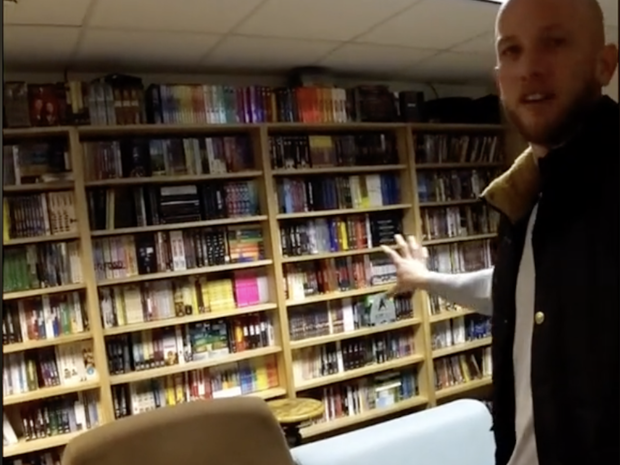 Josiah Horneman standing in front of shelves stocked with DVDs at the Amundsen-Scott South Pole Station.