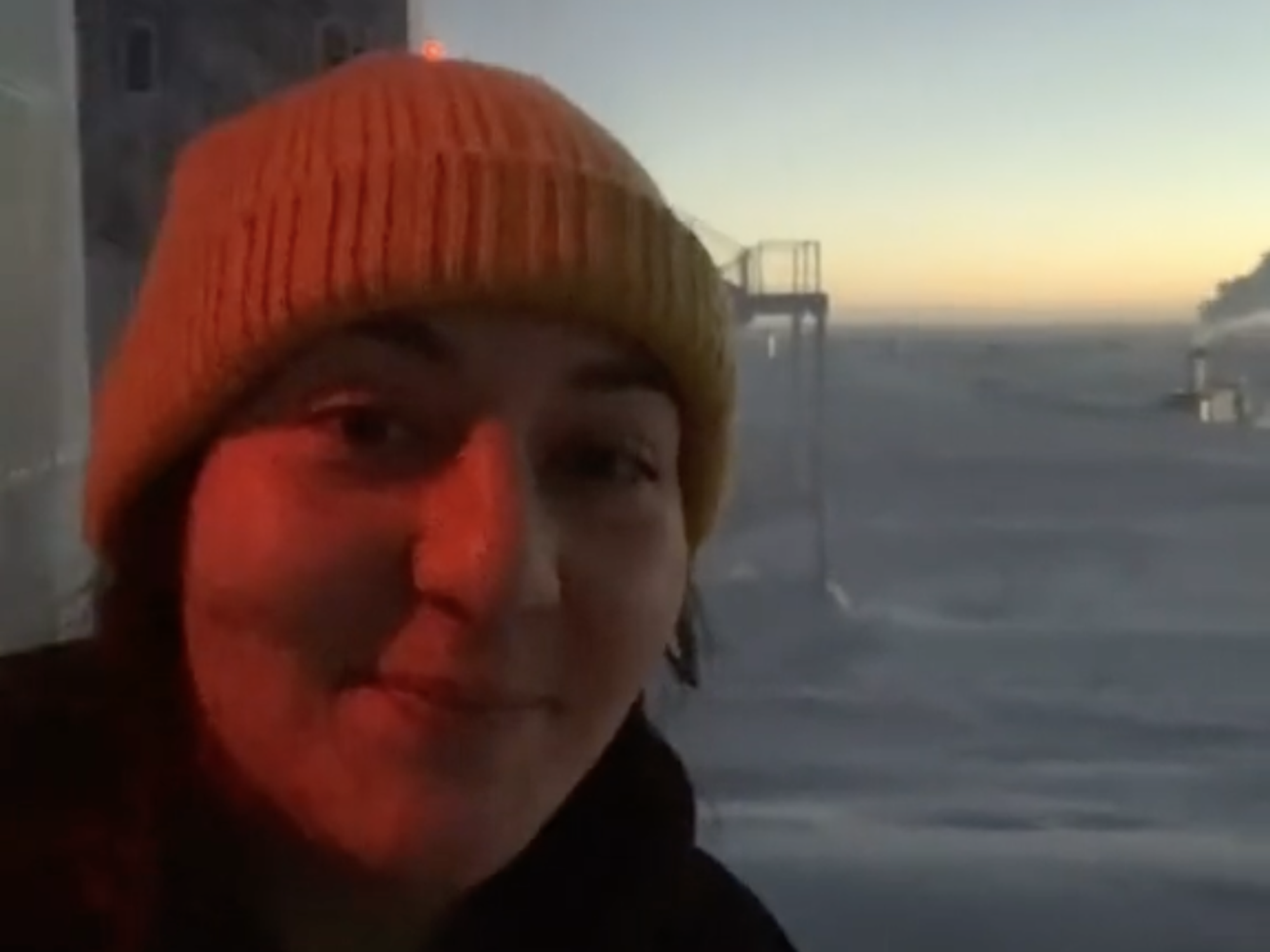 Antoinette "Toni" Traub standing just outside the Amundsen-Scott South Pole Station, behind her the sun is setting in the horizon.