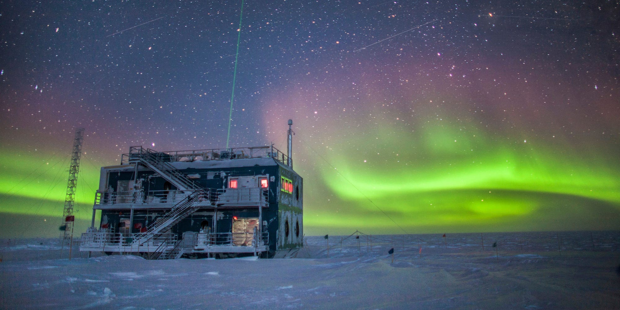 The Atmospheric Research Observatory,  two-storied industrial building, is pictured here at night in 2018 in front of green auroras lighting up the sky in the background.