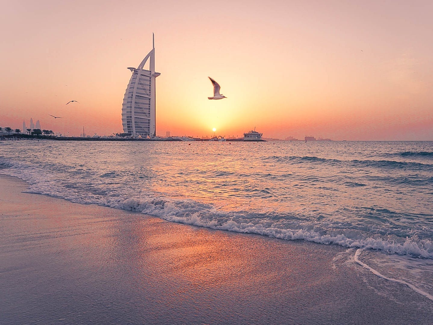 segul flying over the waves crashing over Kite Beach in Dubai at sunset