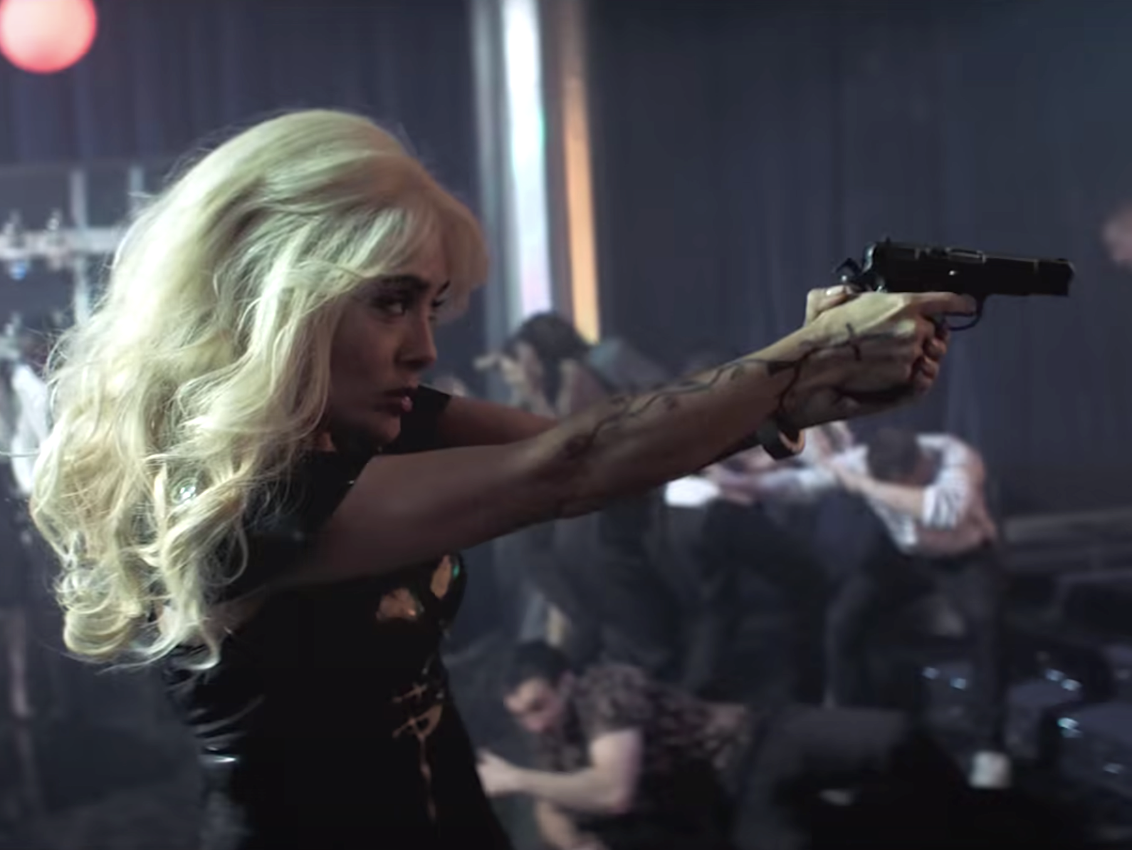 Salma Hayek wearing a blonde wig and point a gun to the right in "The Hitman's Wife's Bodyguard."