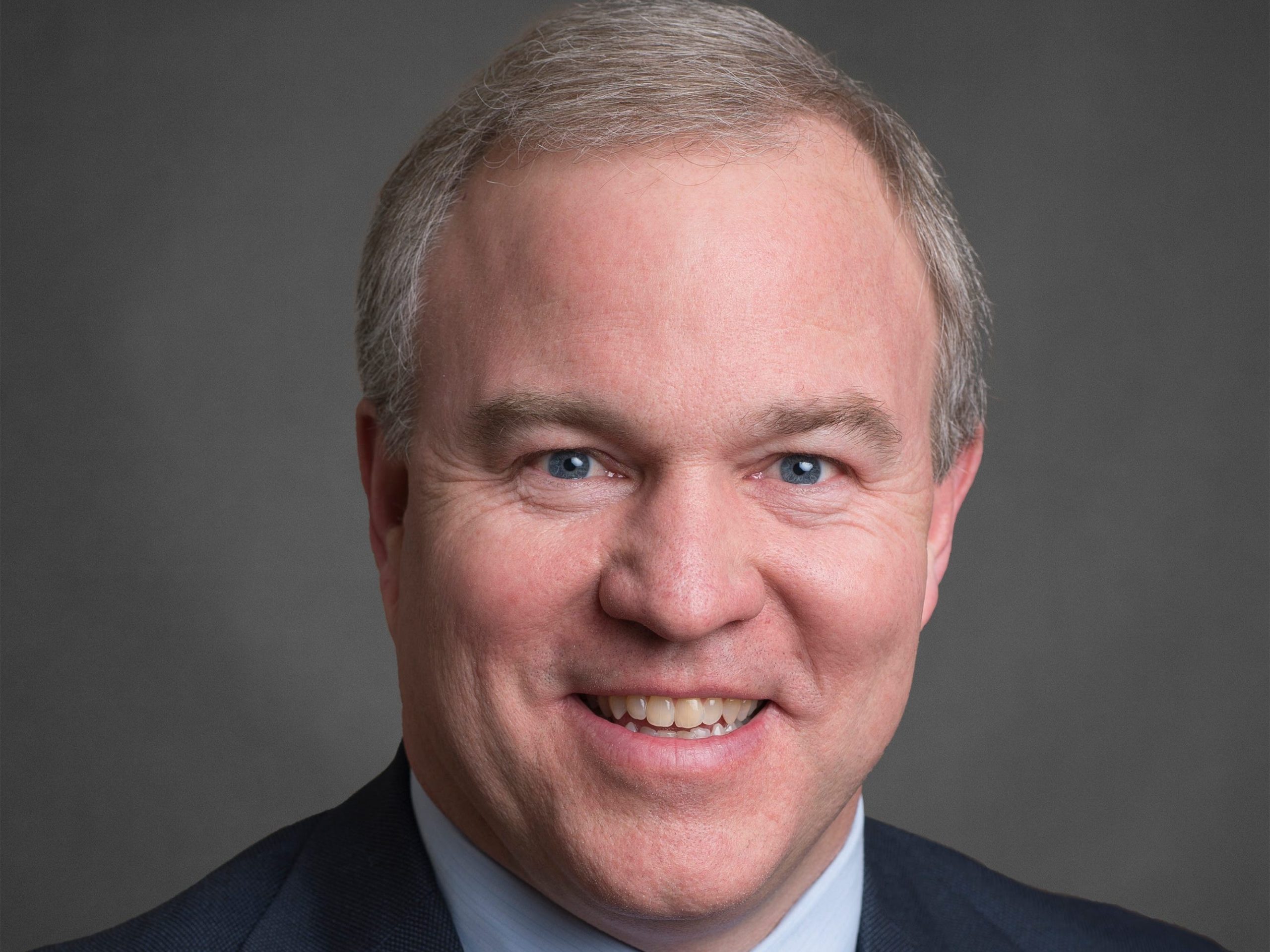 Chris Newman, a top institutional executive at T. Rowe Price, in front of a gray background.