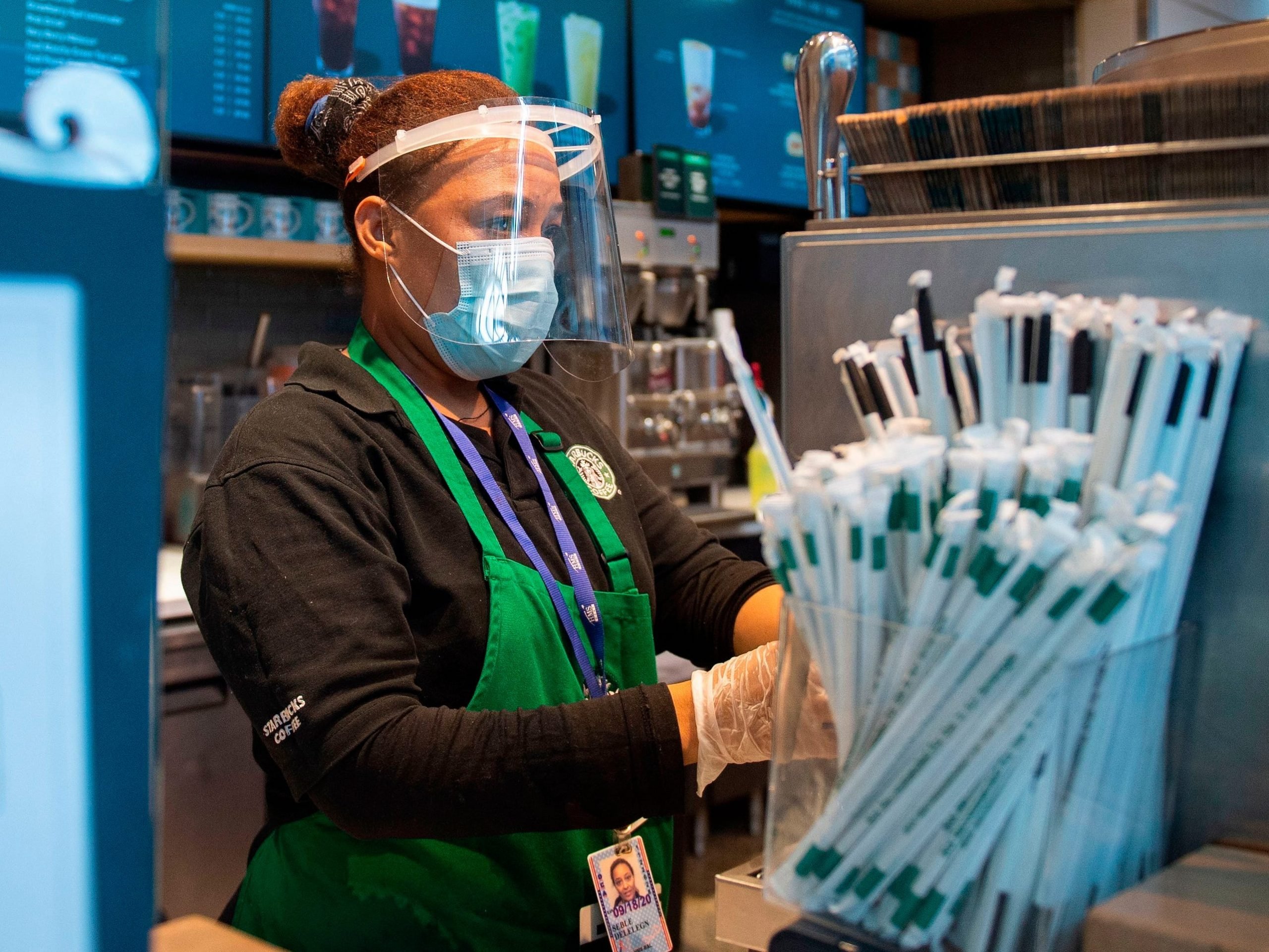 A Starbucks employee wears a face shield and mask as she makes a coffee in Ronald Reagan Washington National Airport in Arlington, Virginia, on May 12, 2020.