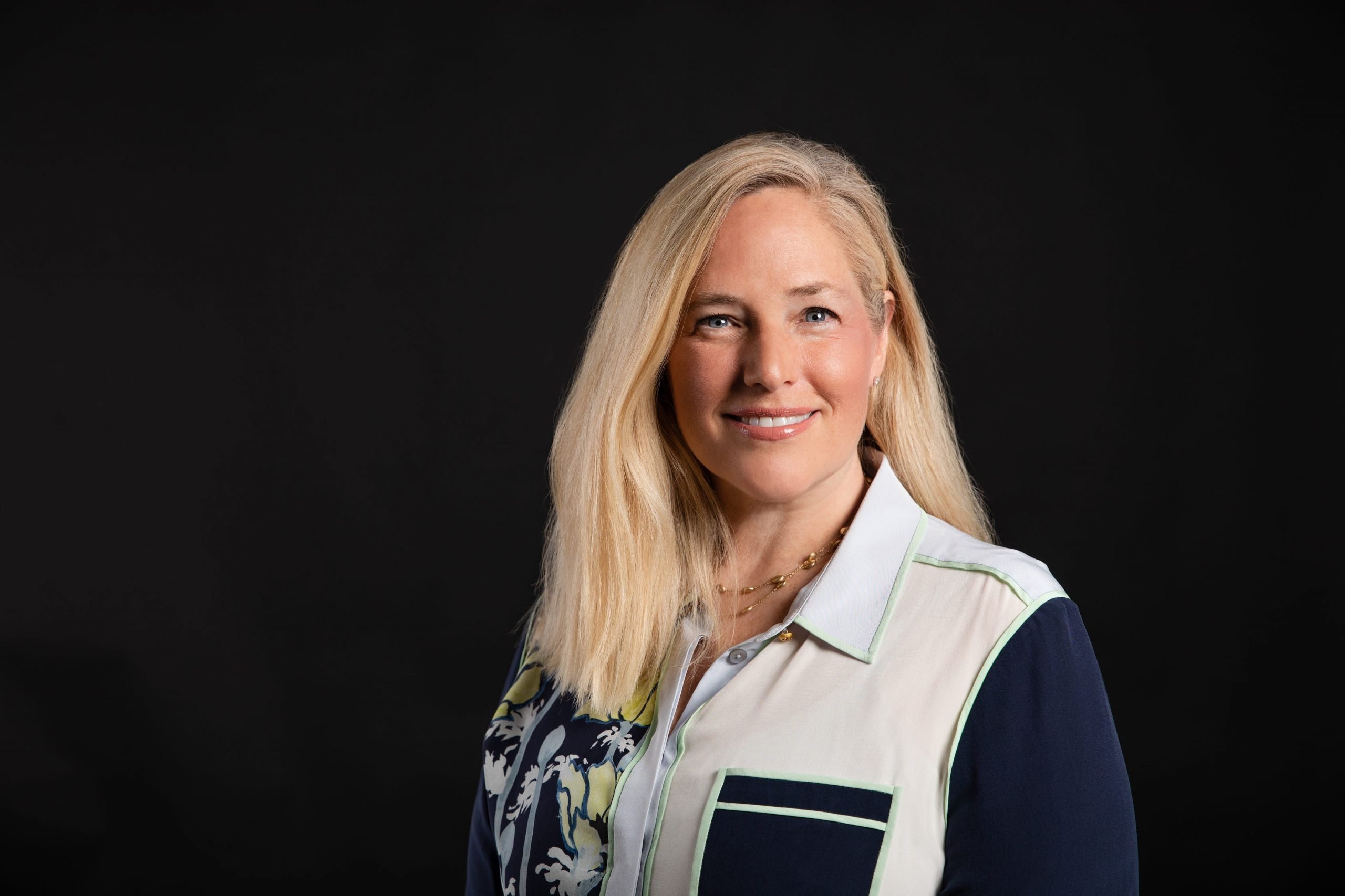 A headshot of Roblox's CMO Barbara Messing who is wearing a blue and white button-up blouse