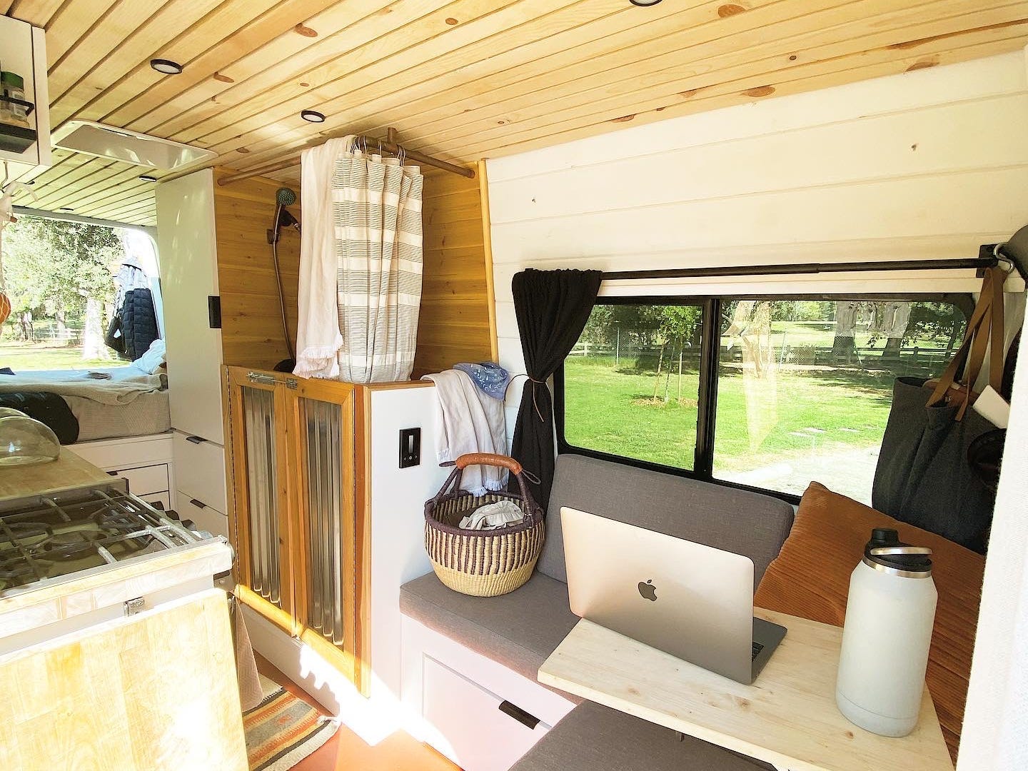The inside of a van with a small couch, table, bathroom, and kitchen.