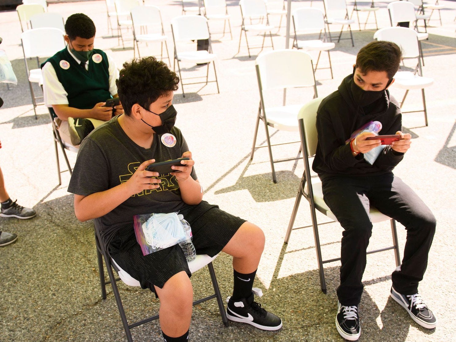 teenagers wait and play games after getting COVID-19 shots