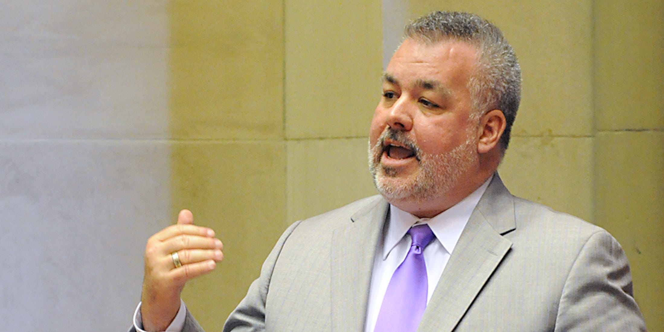 New York Assemblyman Danny O'Donnell speaks on the floor of the assembly surrounded by LGBT pride flags.