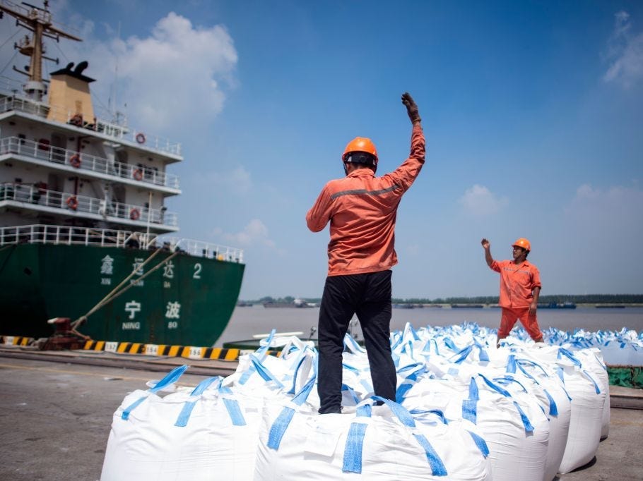 This photo taken on August 7, 2018 shows workers unloading bags of chemicals at a port in Zhangjiagang in China's eastern Jiangsu province