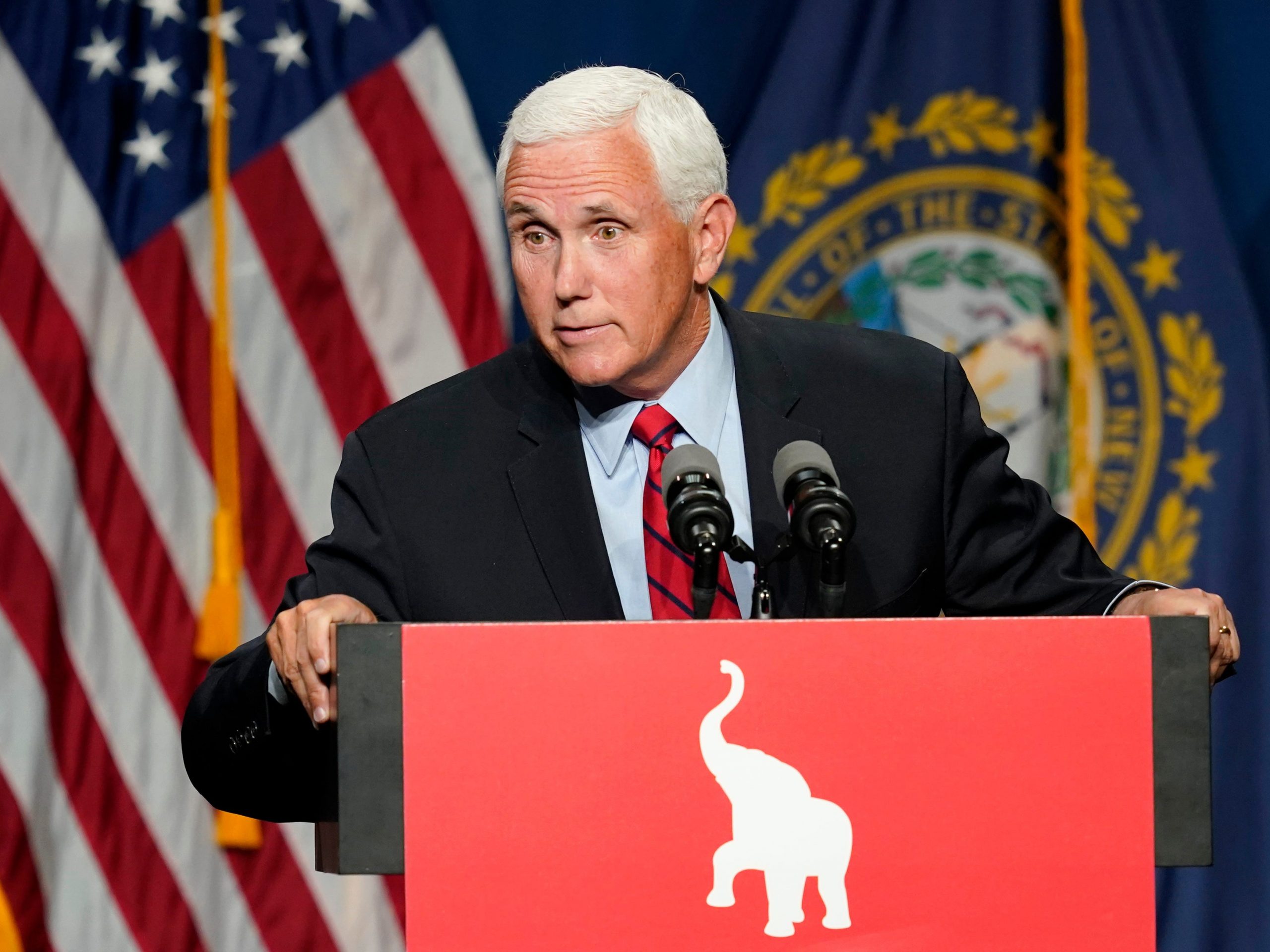 Mike Pence speaks at a red podium with en elephant symbol on it in front of an American flag.