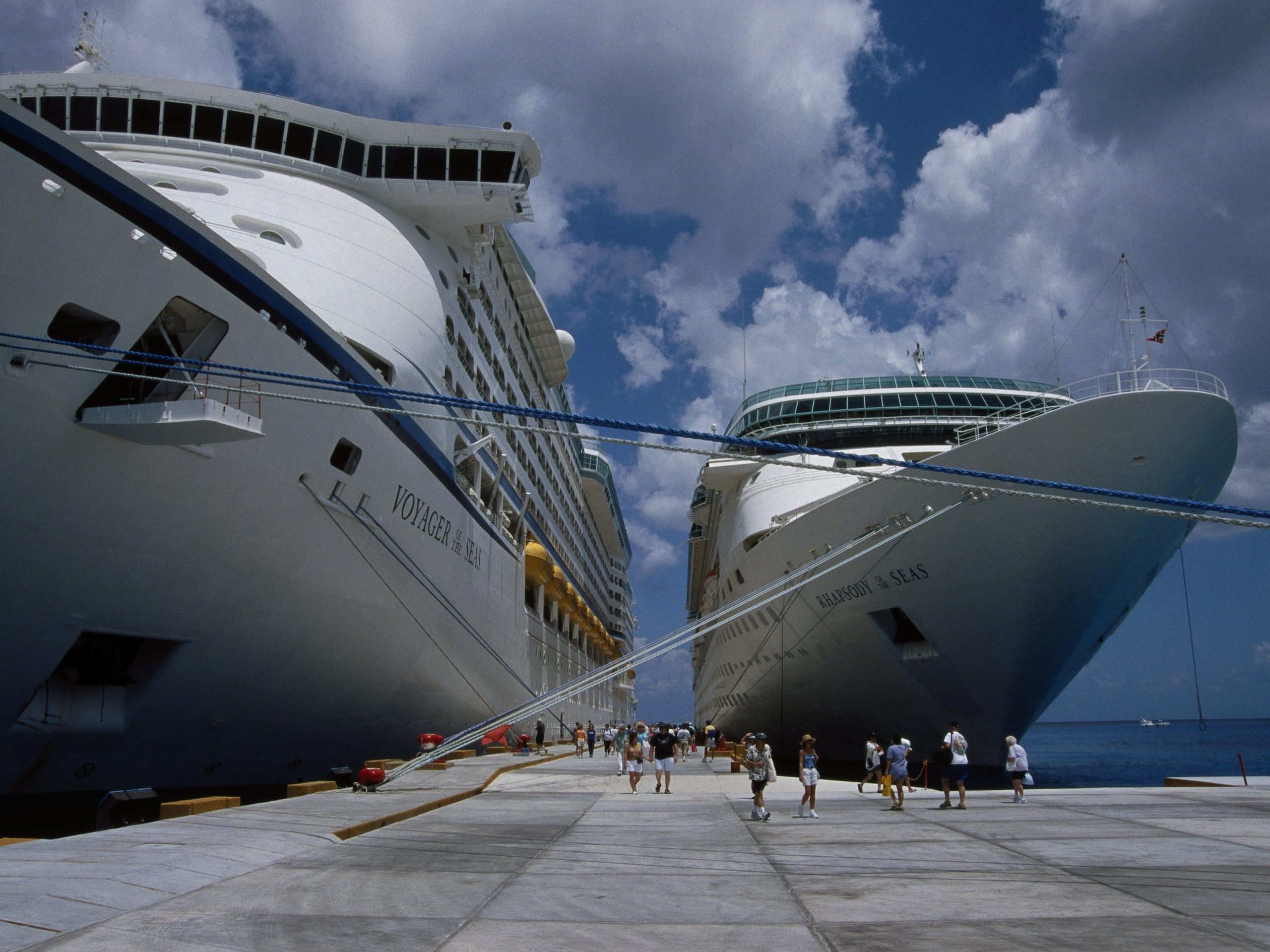 Picture of two cruise ships docking and people leaving.