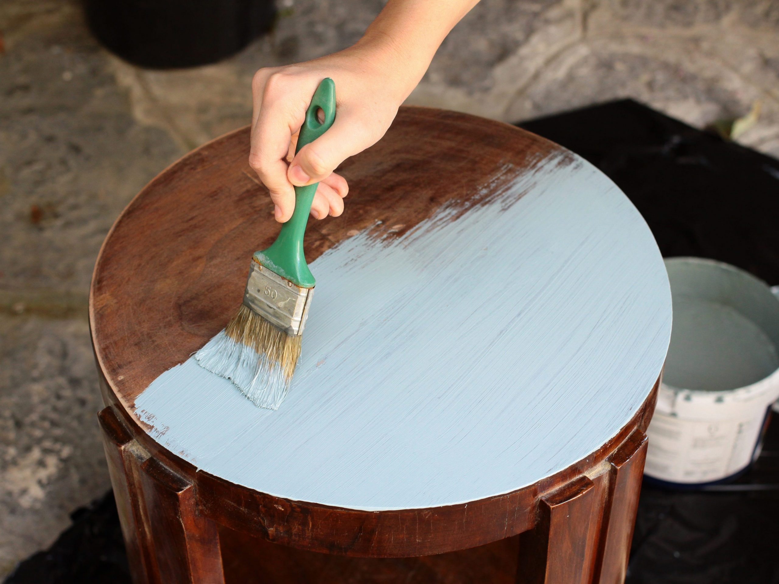 hand painting a brown wooden end table light blue