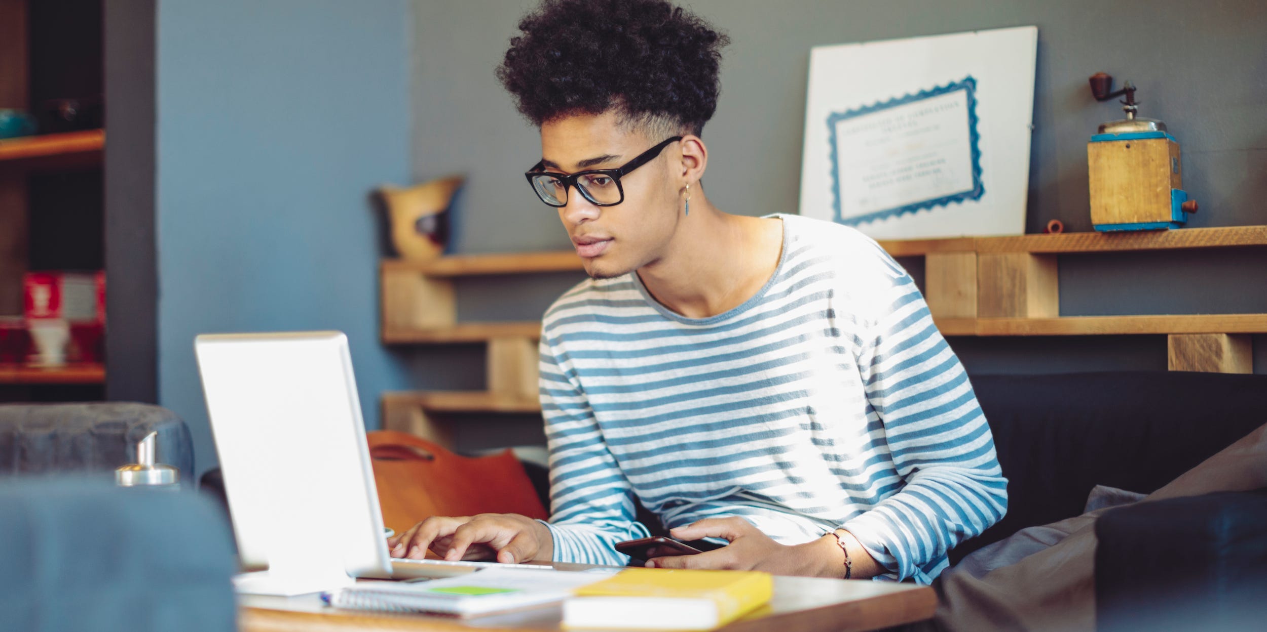 student using laptop with textbooks open at desk