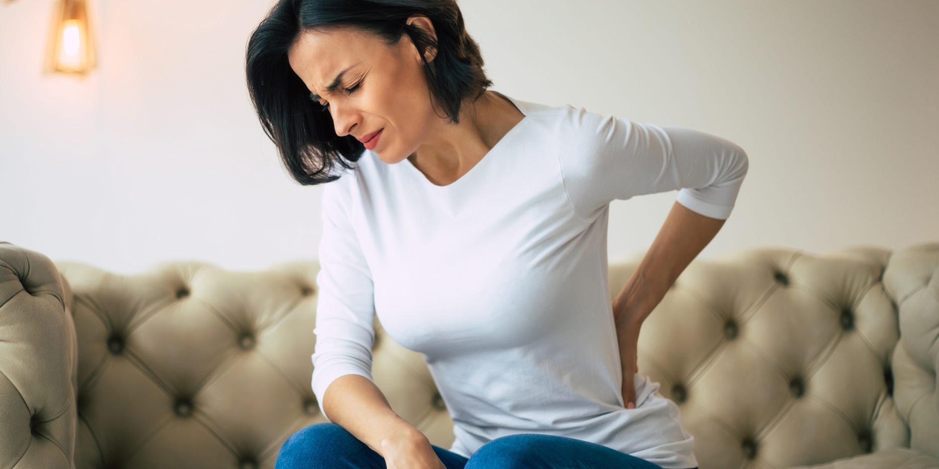 woman clutching lower left back in pain